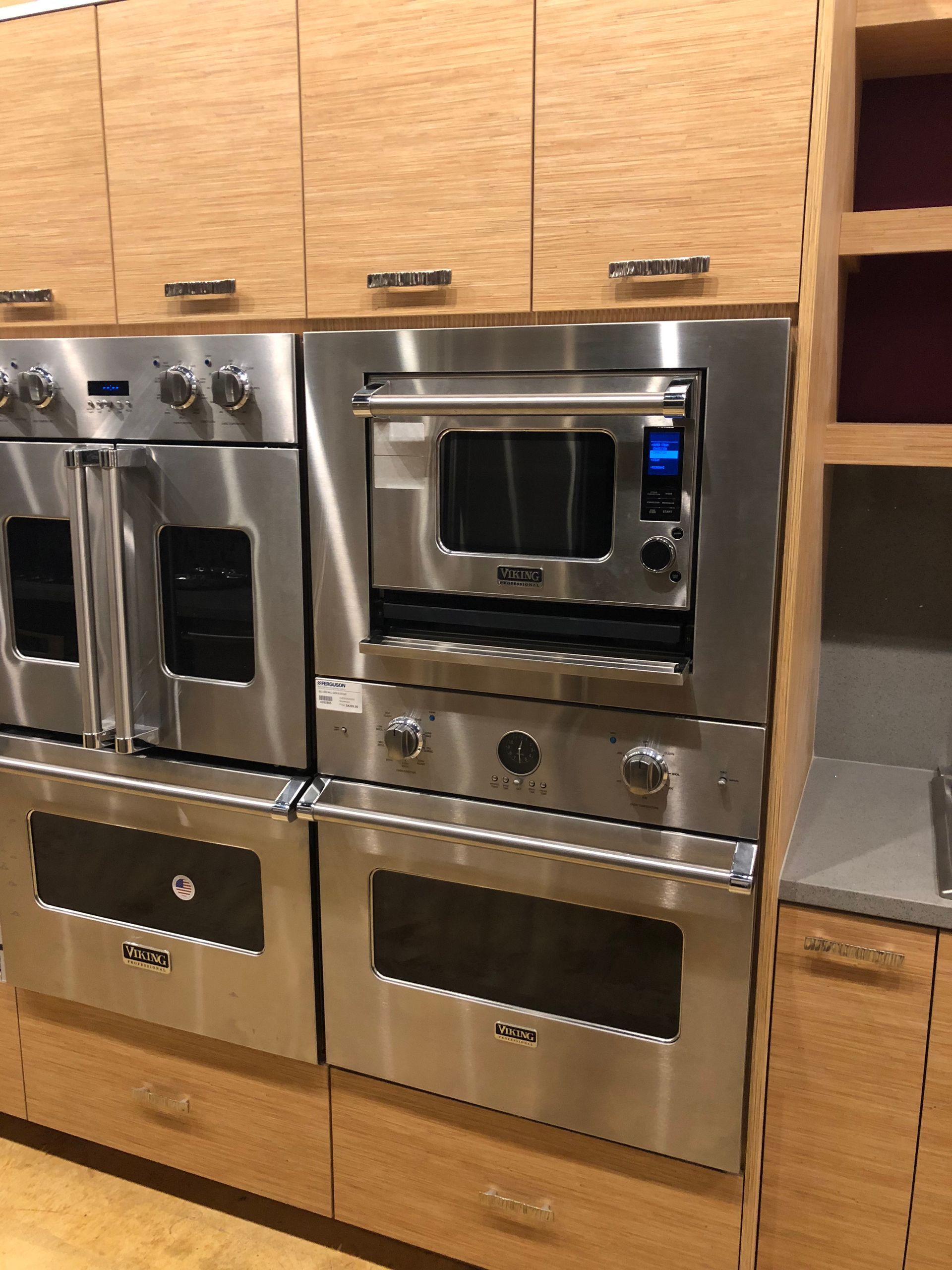 Stainless steel kitchen appliances built into light wood cabinetry.