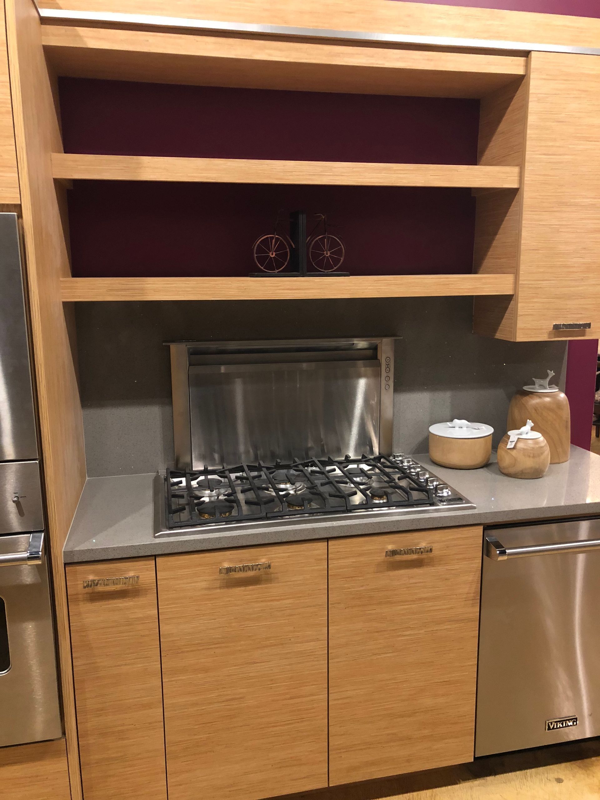 Kitchen with wood cabinets, stainless steel stove, and open shelving with decorative items.