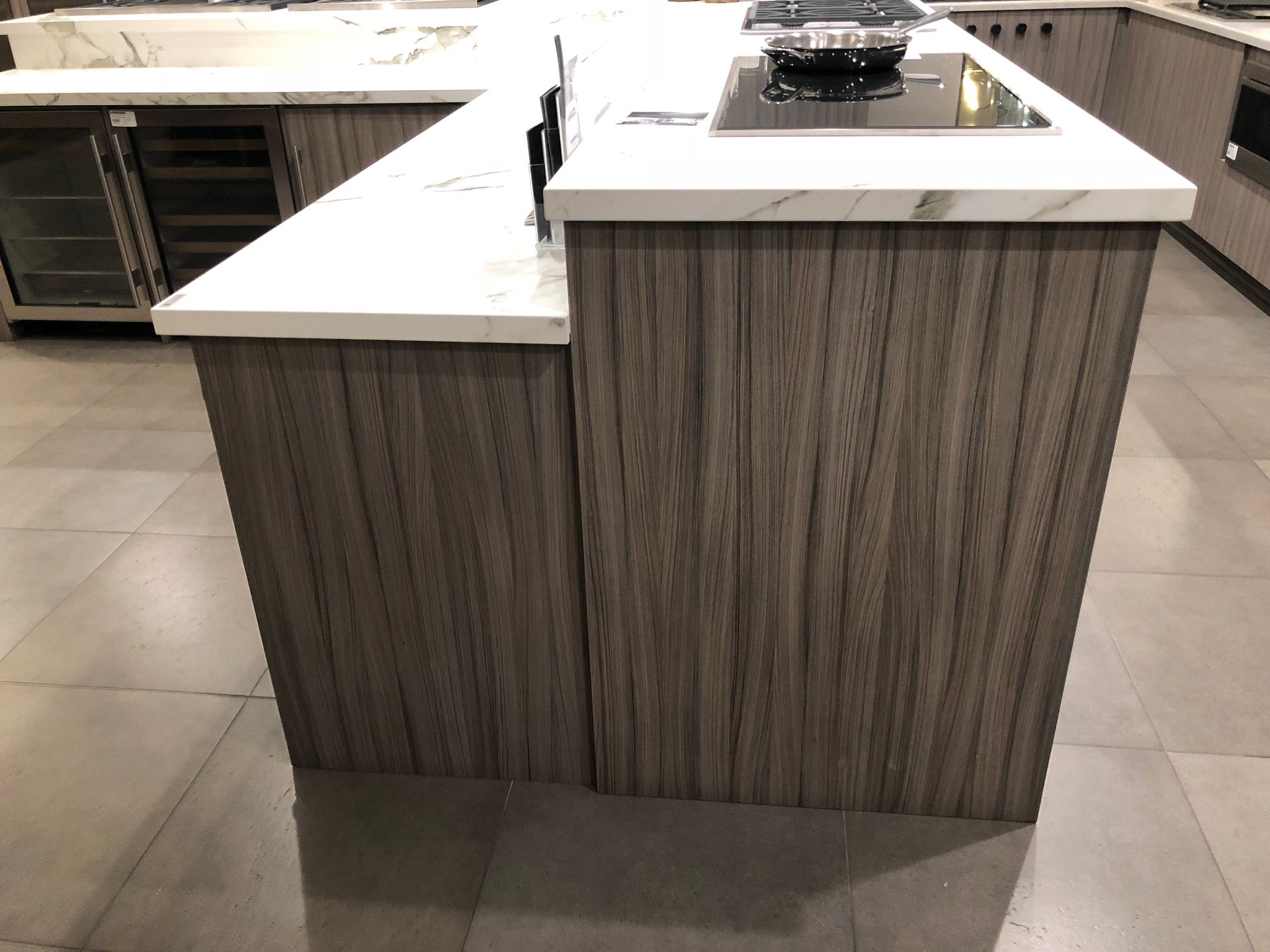 Kitchen island with a wooden facade, white countertop, and a built-in stovetop.