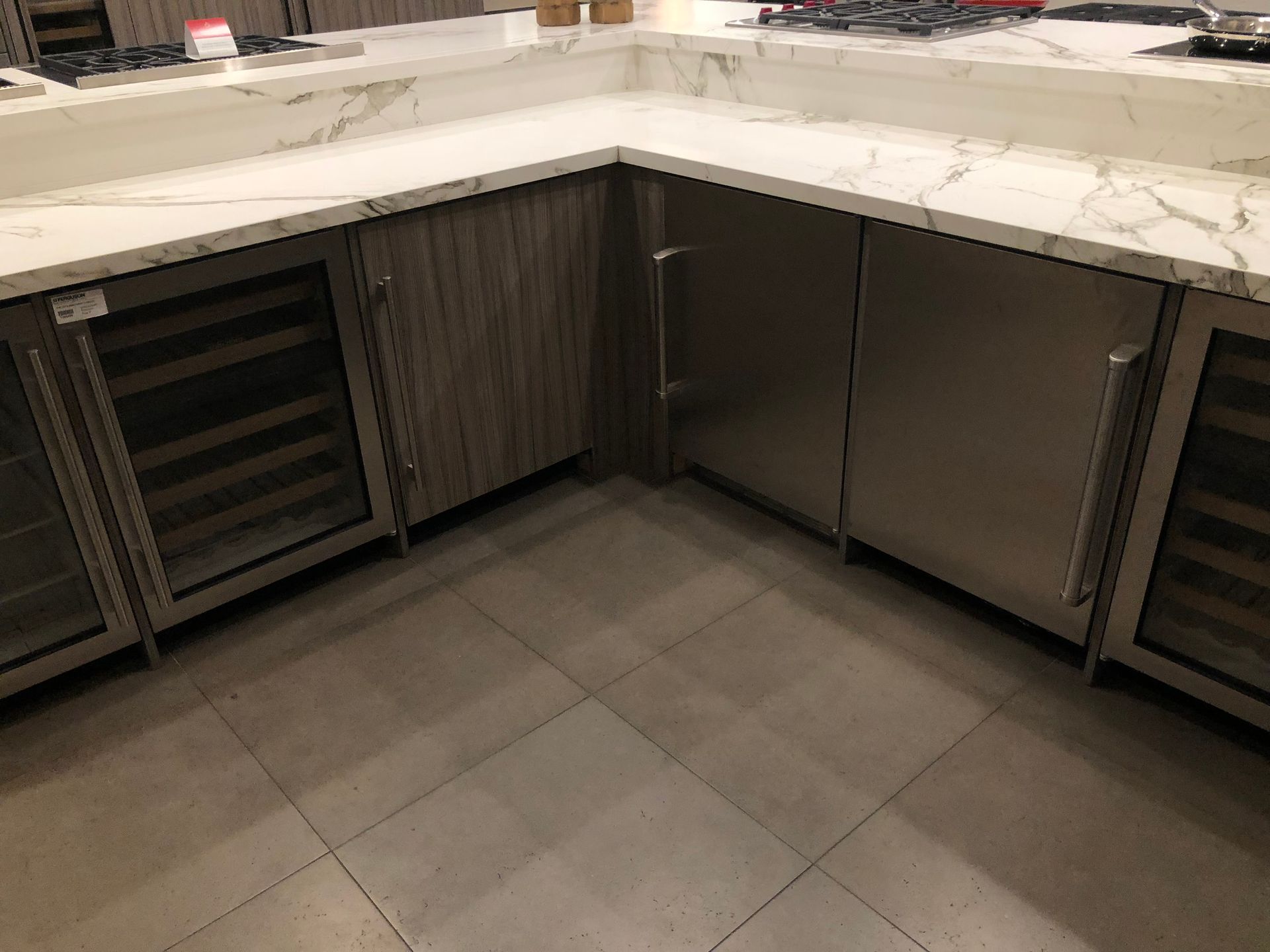 Kitchen corner with marble countertops, built-in stainless steel appliances, and wood cabinets on tile floor.