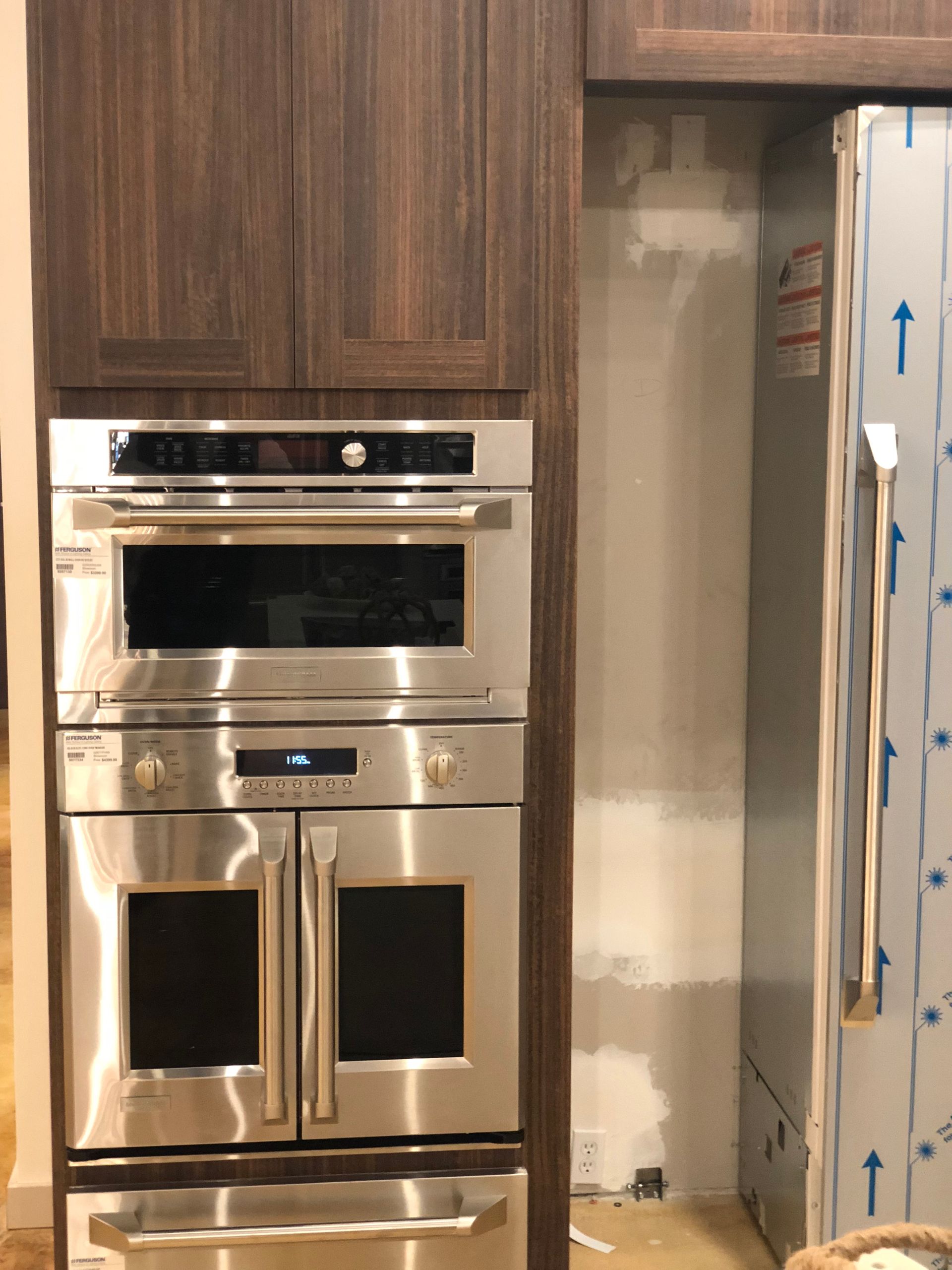 Stainless steel oven and microwave built into wood cabinets next to a refrigerator.