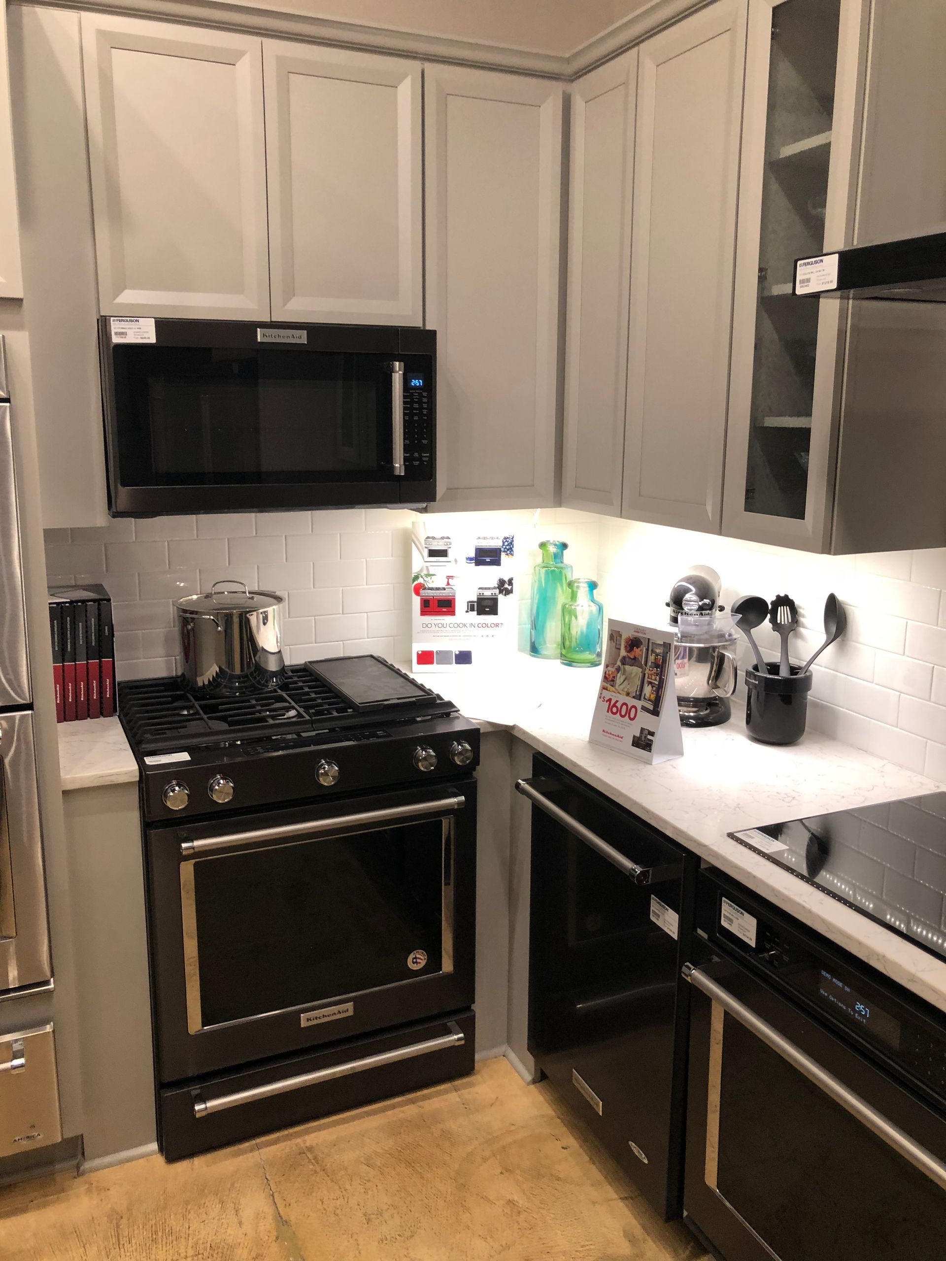 Small kitchen corner with light gray cabinets, black appliances, and white countertops.