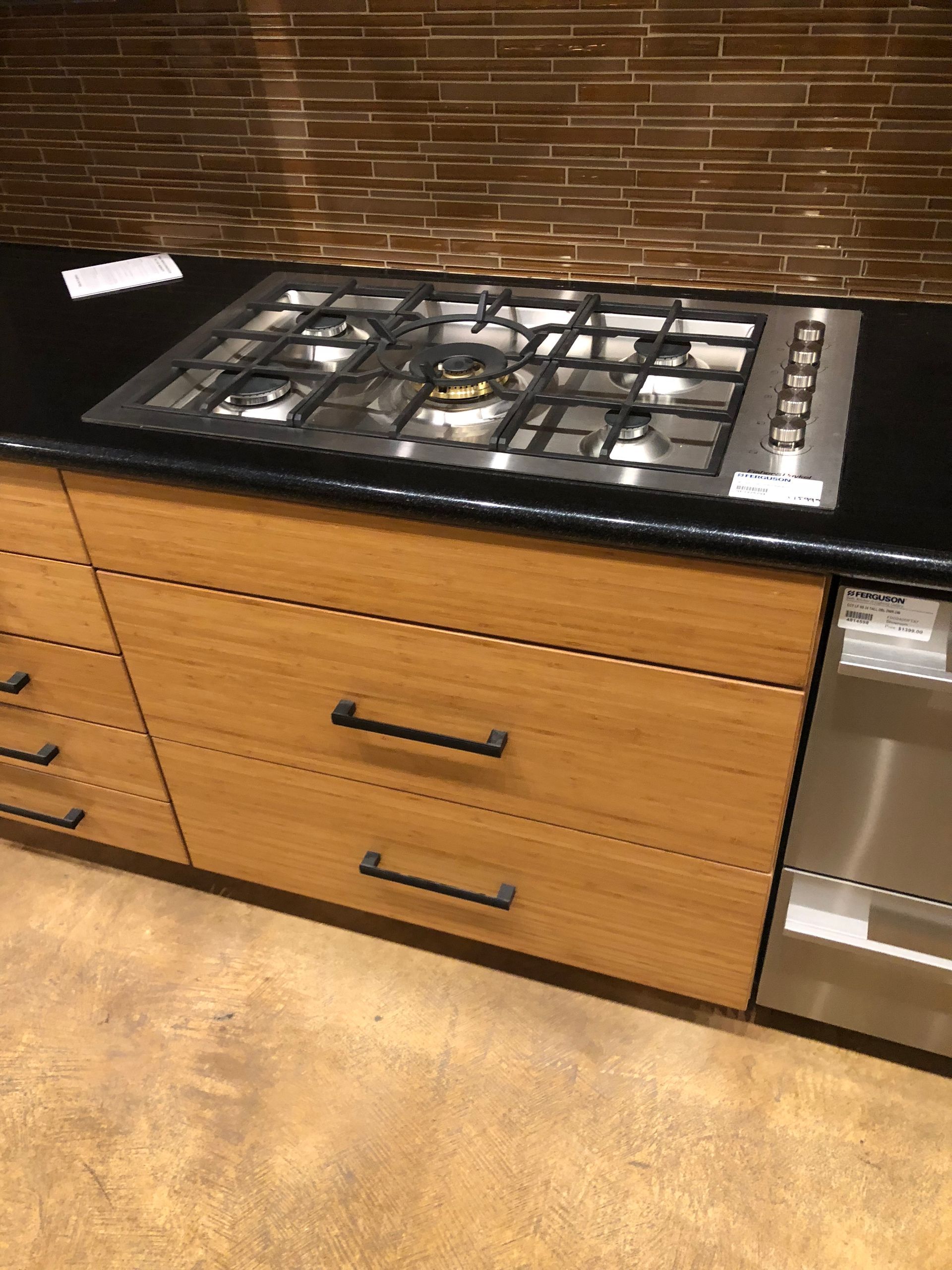 A kitchen with a black countertop, gas cooktop, and wooden cabinets.