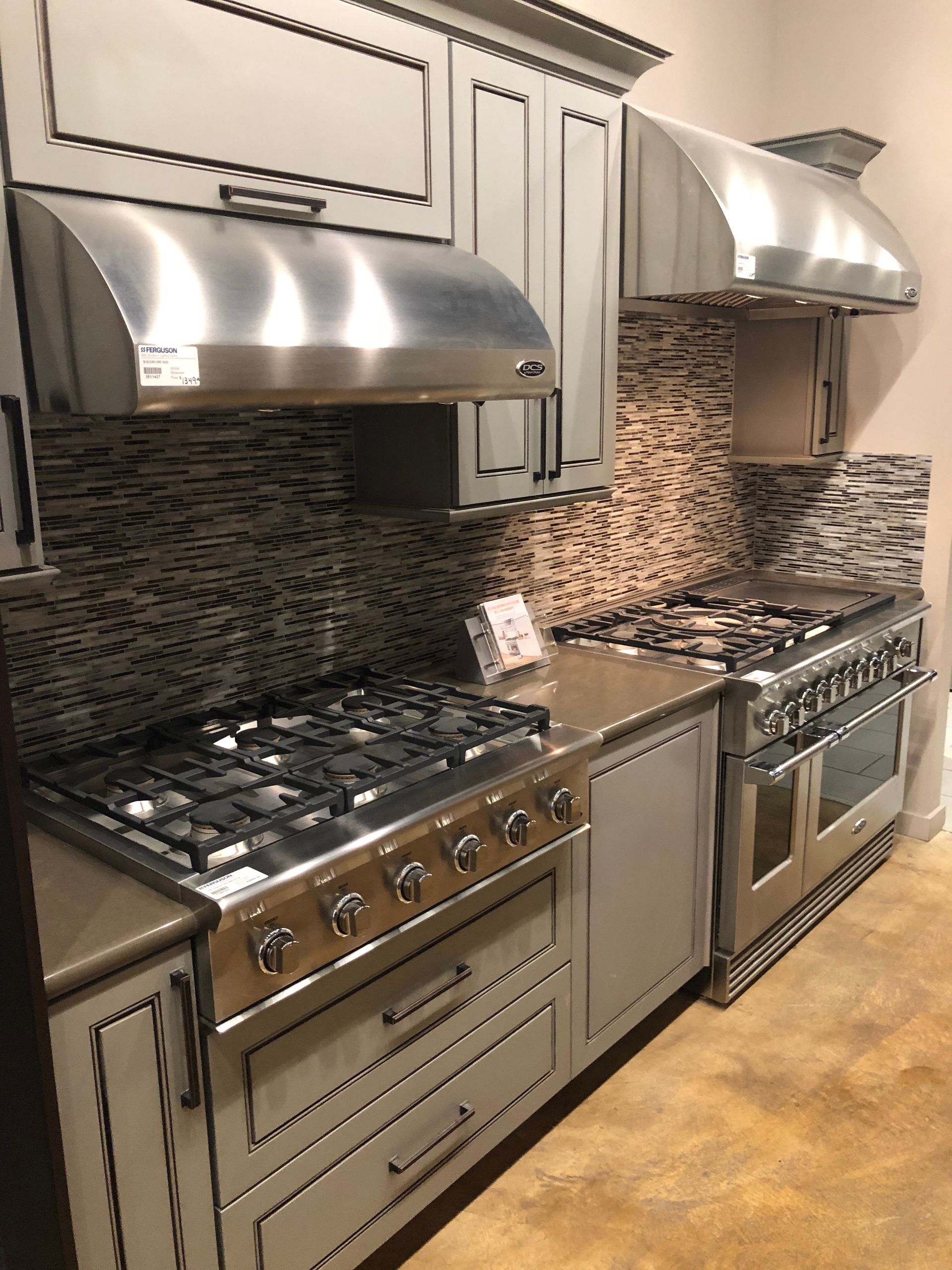 Kitchen with gray cabinets, stainless steel appliances, and a mosaic tile backsplash.
