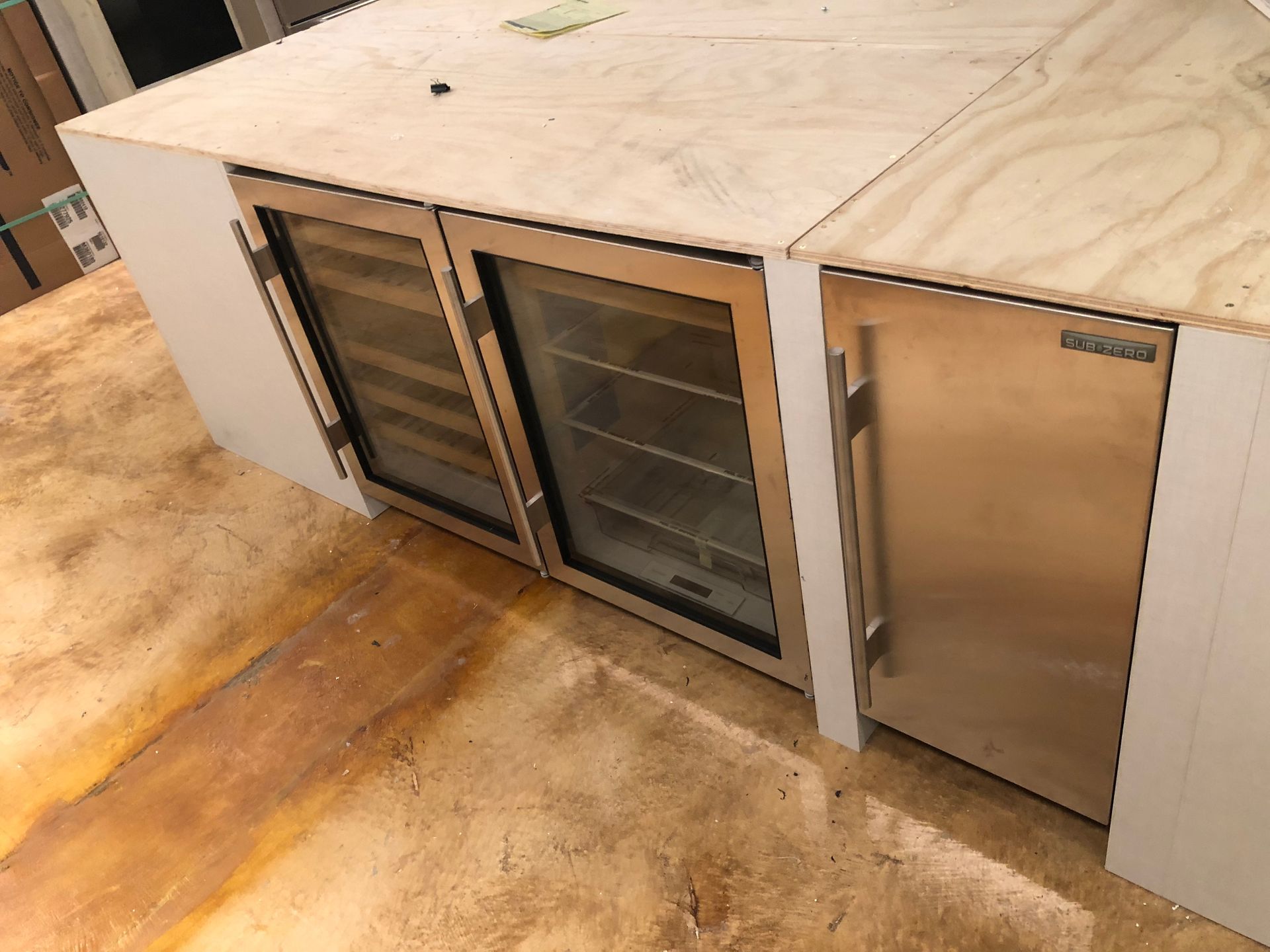 Built-in kitchen island with a wine fridge and refrigerator; light wood countertop, stainless steel appliances.