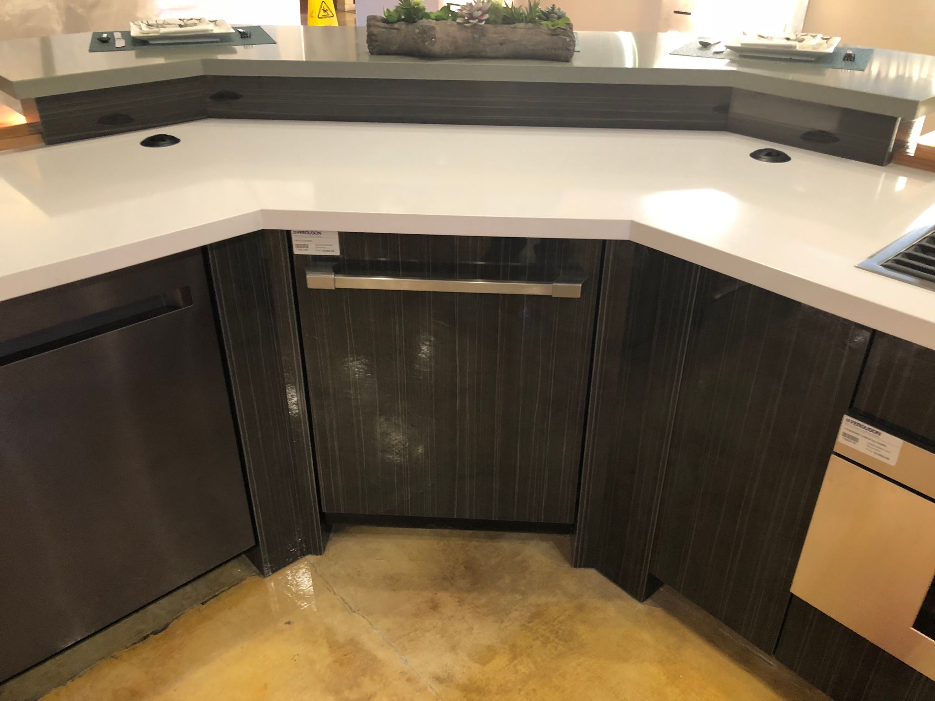 Kitchen island with a dishwasher and cabinets, dark wood grain, light countertop.
