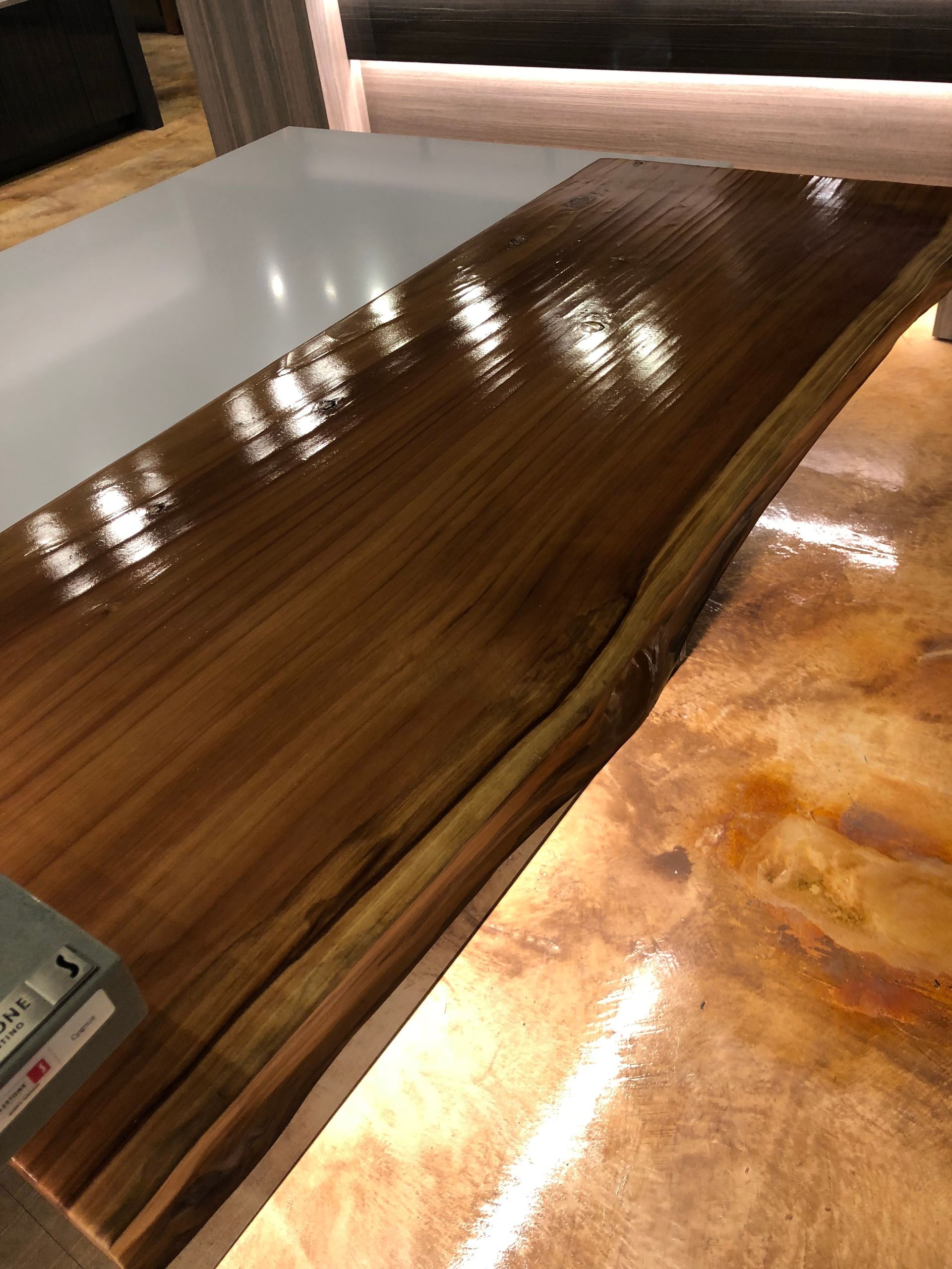 A shiny, varnished wooden countertop with a live edge next to a copper-toned countertop.