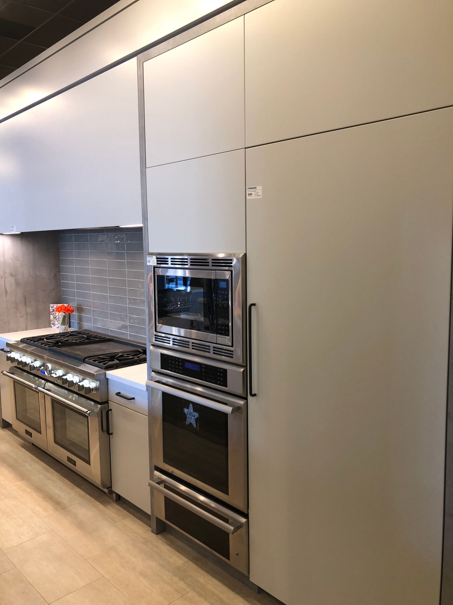 Modern kitchen with stainless steel oven, stove, and light gray cabinets.