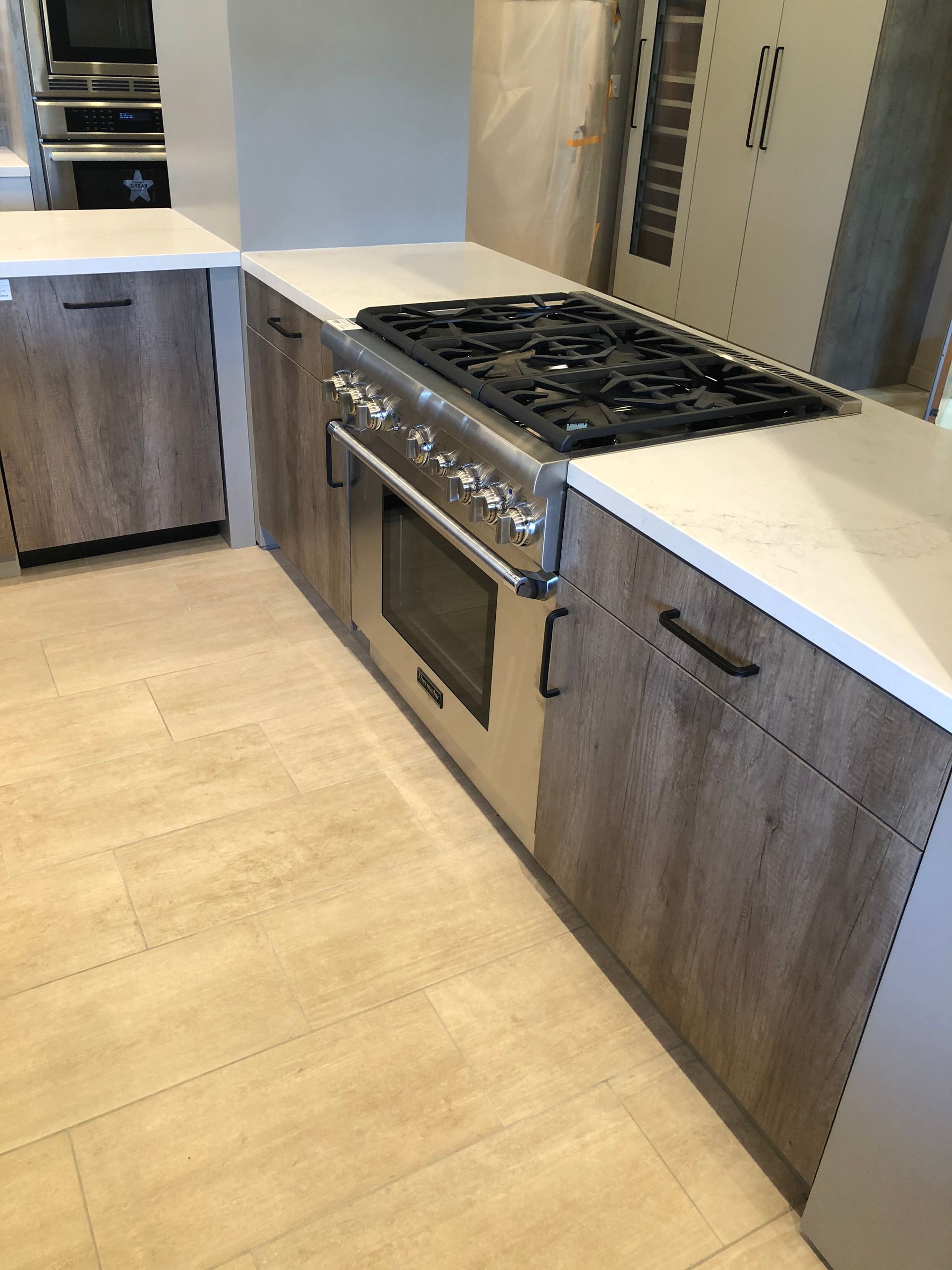 Kitchen island with a stainless steel oven/stove and light wood-look cabinets. Light countertops and flooring.