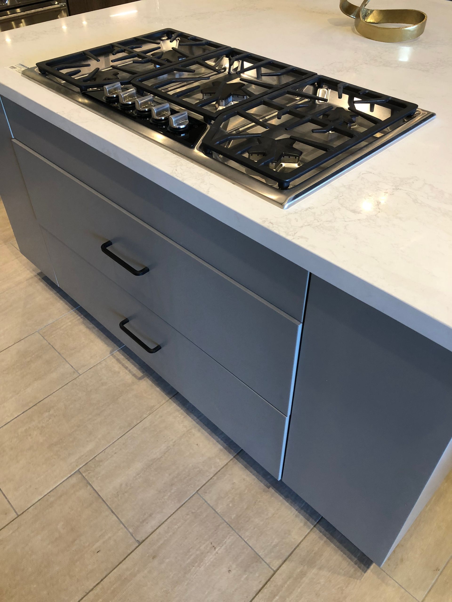 Kitchen island with gas stovetop, gray cabinets, and black drawer pulls.