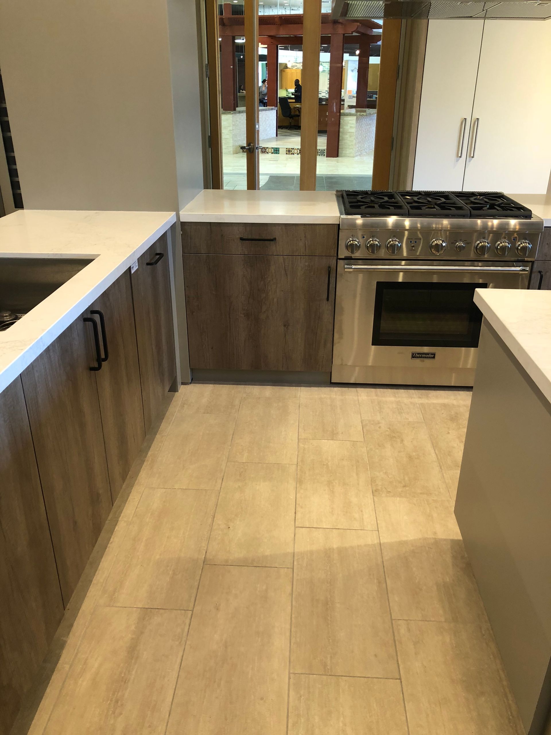 Kitchen with wood cabinets, white countertops, stainless steel range, and light tile flooring.