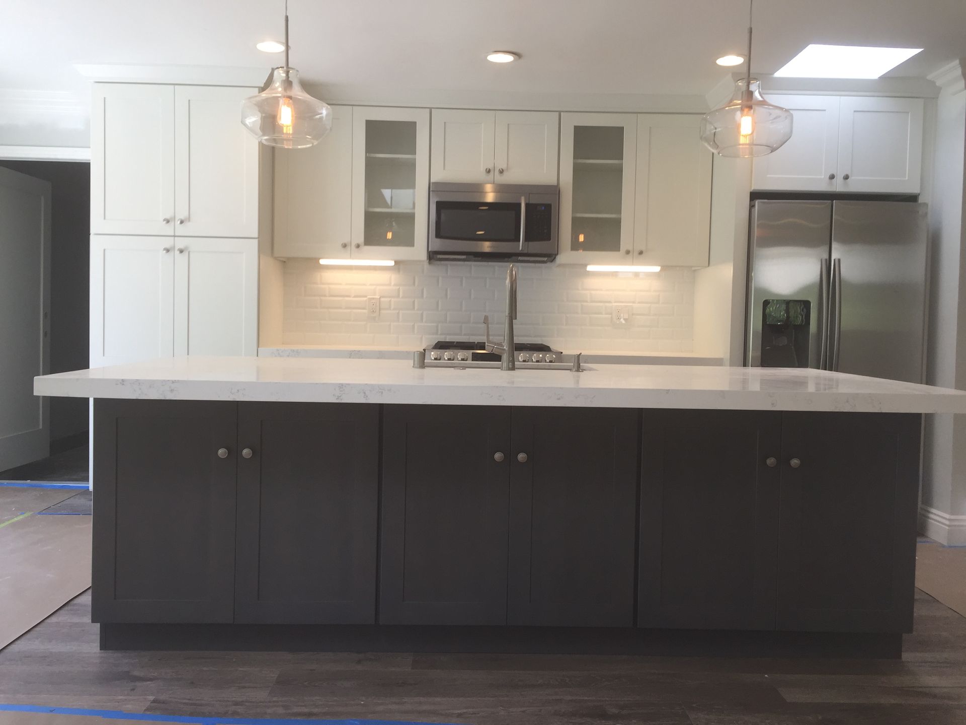 Modern kitchen with white and gray cabinets, stainless steel appliances, and a large island.