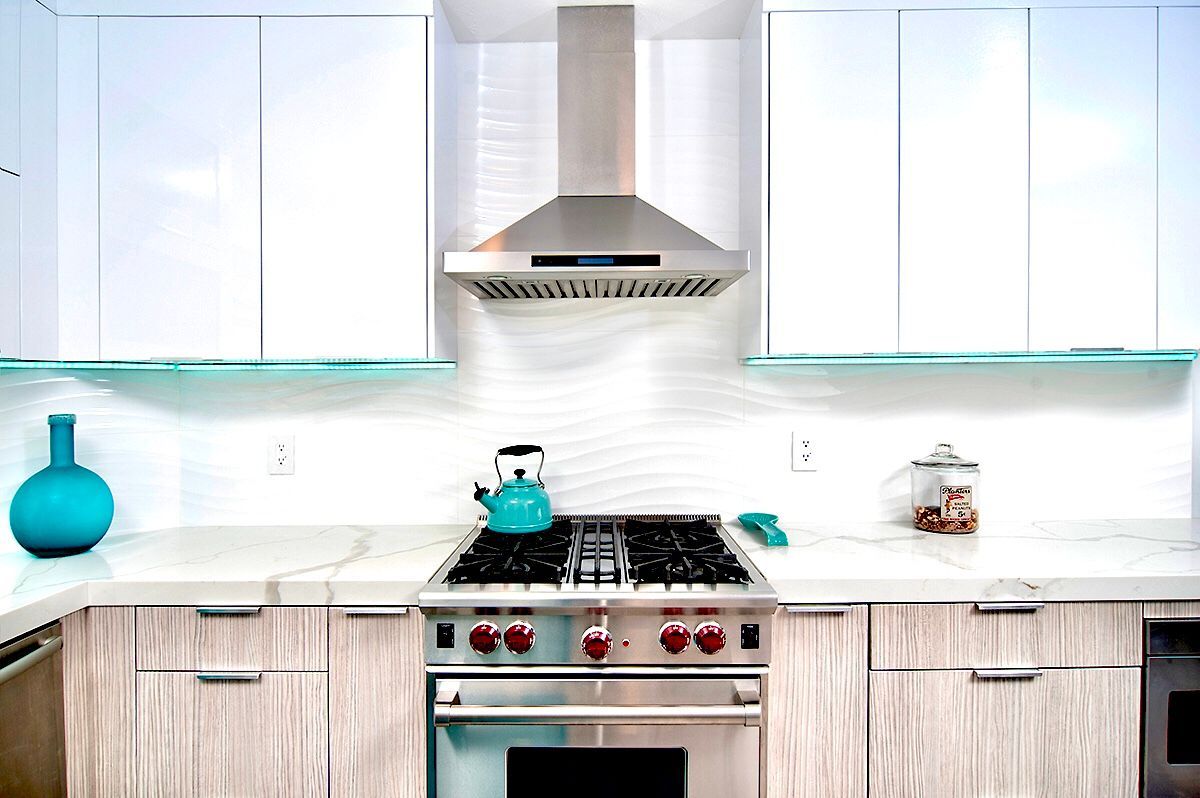 Modern kitchen with stainless steel range, white cabinets, turquoise accents.