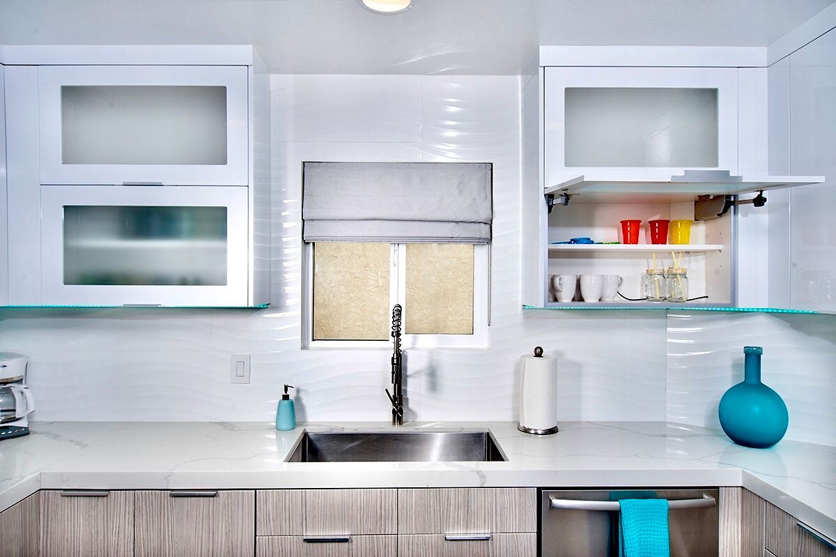 Modern kitchen with white and gray cabinets, stainless steel sink, and aqua accents.
