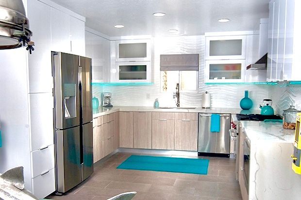 Modern kitchen with light wood and white cabinets, stainless steel appliances, and turquoise accents.