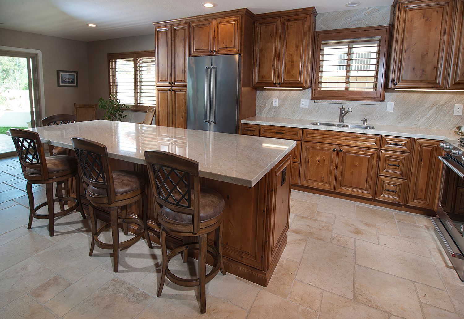 Spacious kitchen with wooden cabinets, a large island with seating, and a stainless steel refrigerator.