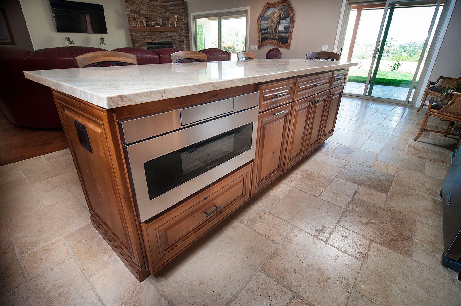Kitchen island with built-in microwave and wood cabinets, marble countertop.