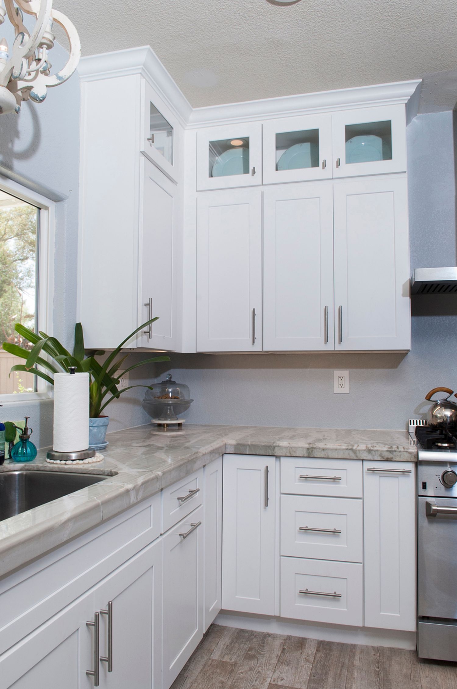 White kitchen cabinets with countertop, window, and stainless steel appliances.