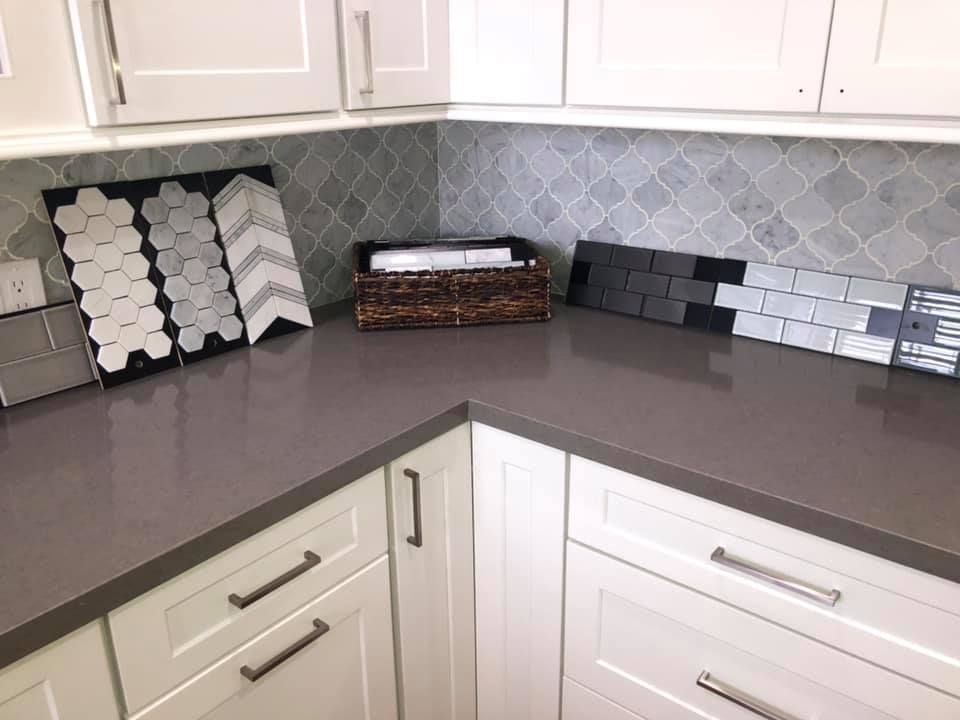 A kitchen with white cabinets and a counter top with tiles on it.