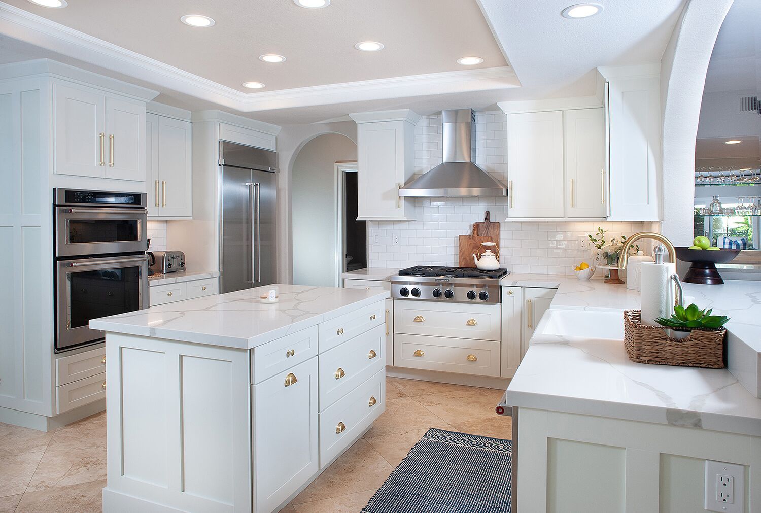 White kitchen with marble countertops, stainless steel appliances, and an island.