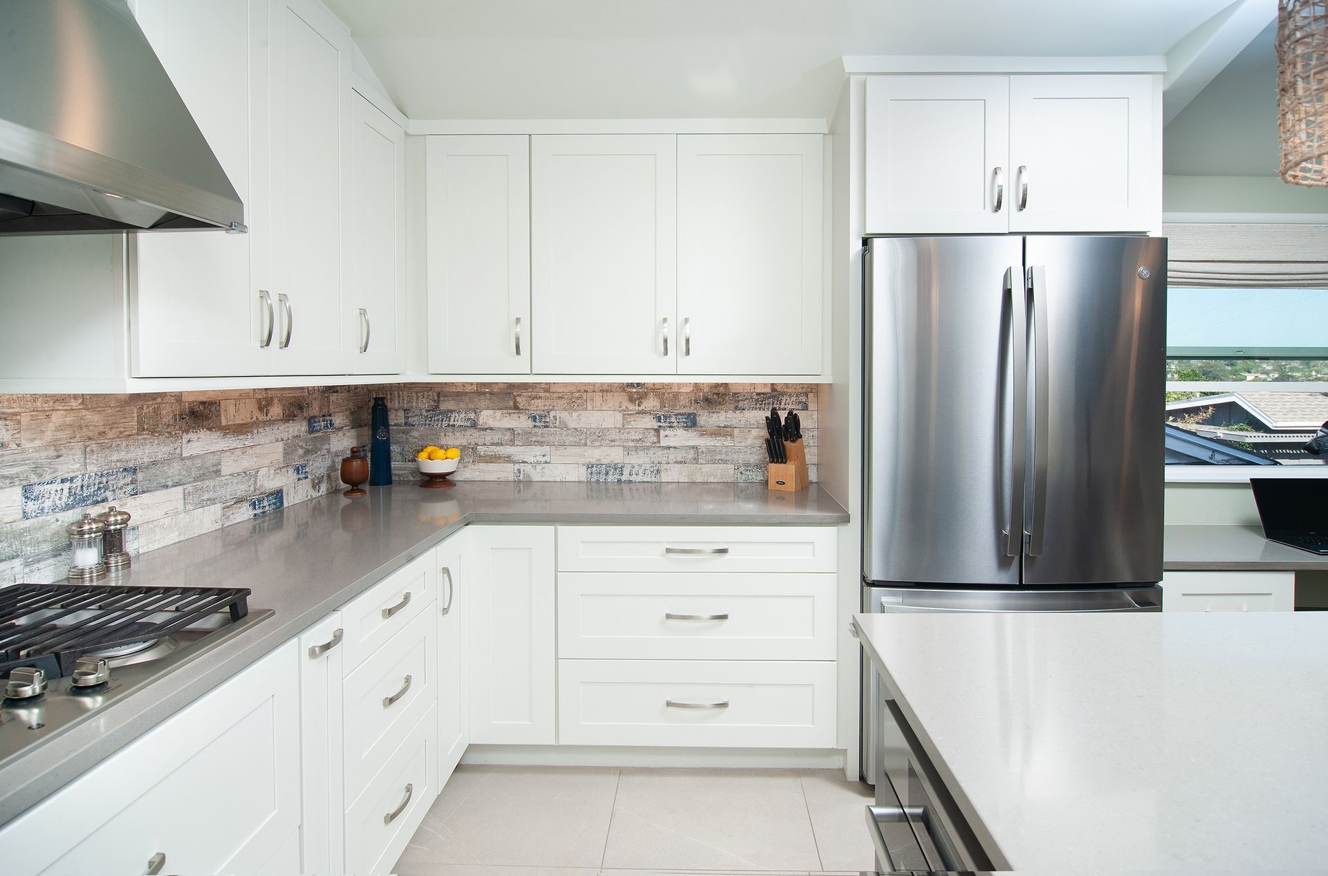White kitchen with stainless steel appliances and a light-colored countertop.