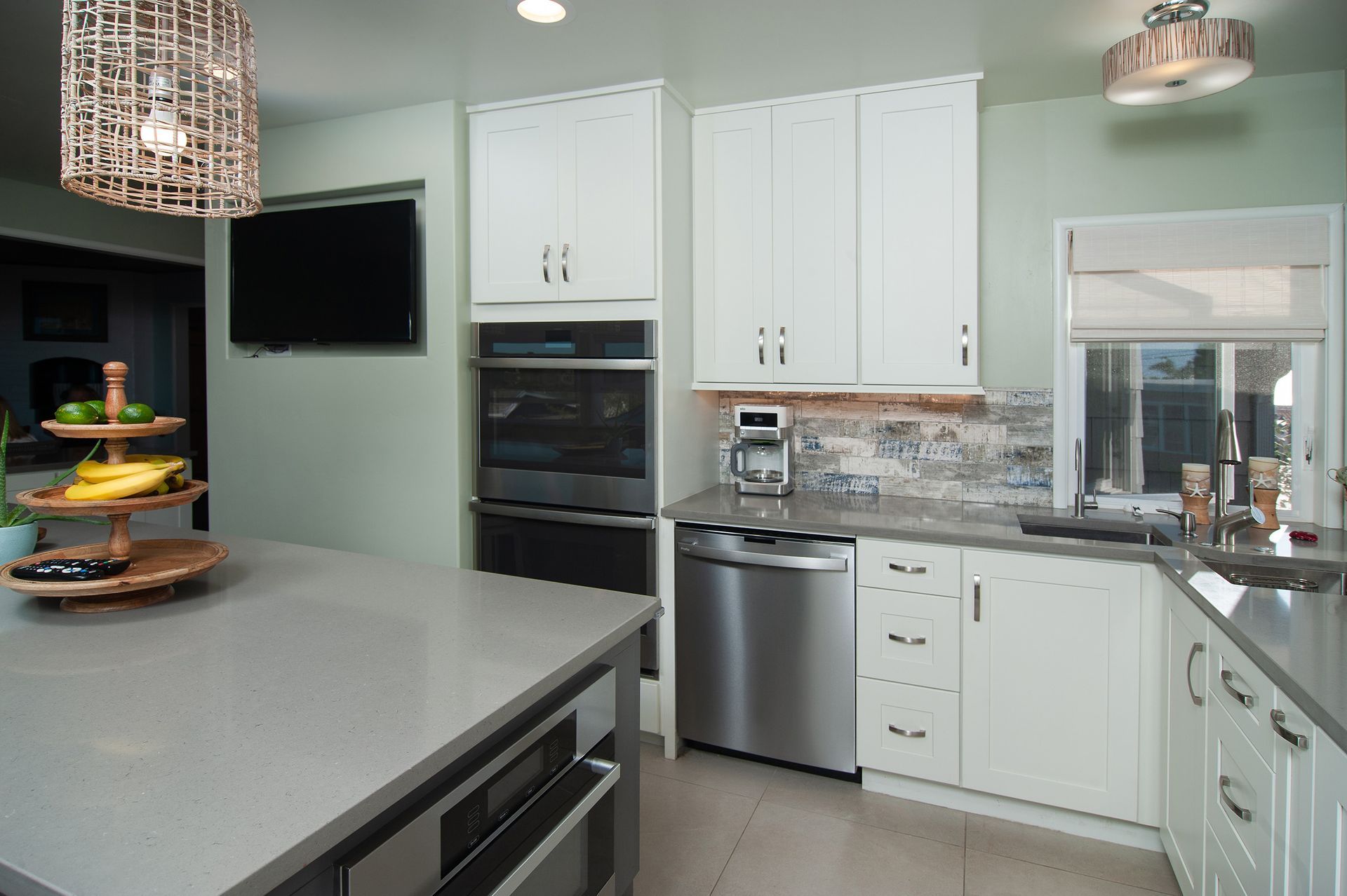 Modern kitchen with white cabinets, grey countertops, stainless steel appliances, and a center island.