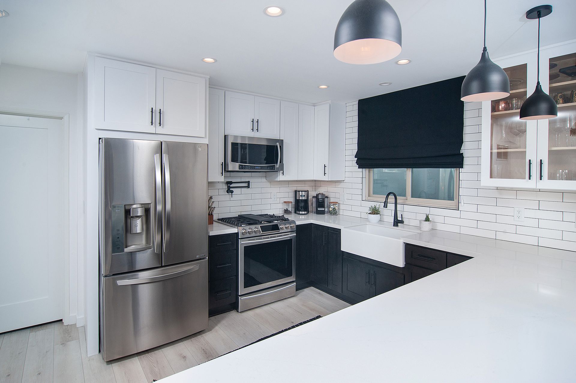 Modern kitchen with white and dark cabinets, stainless steel appliances, and pendant lights.