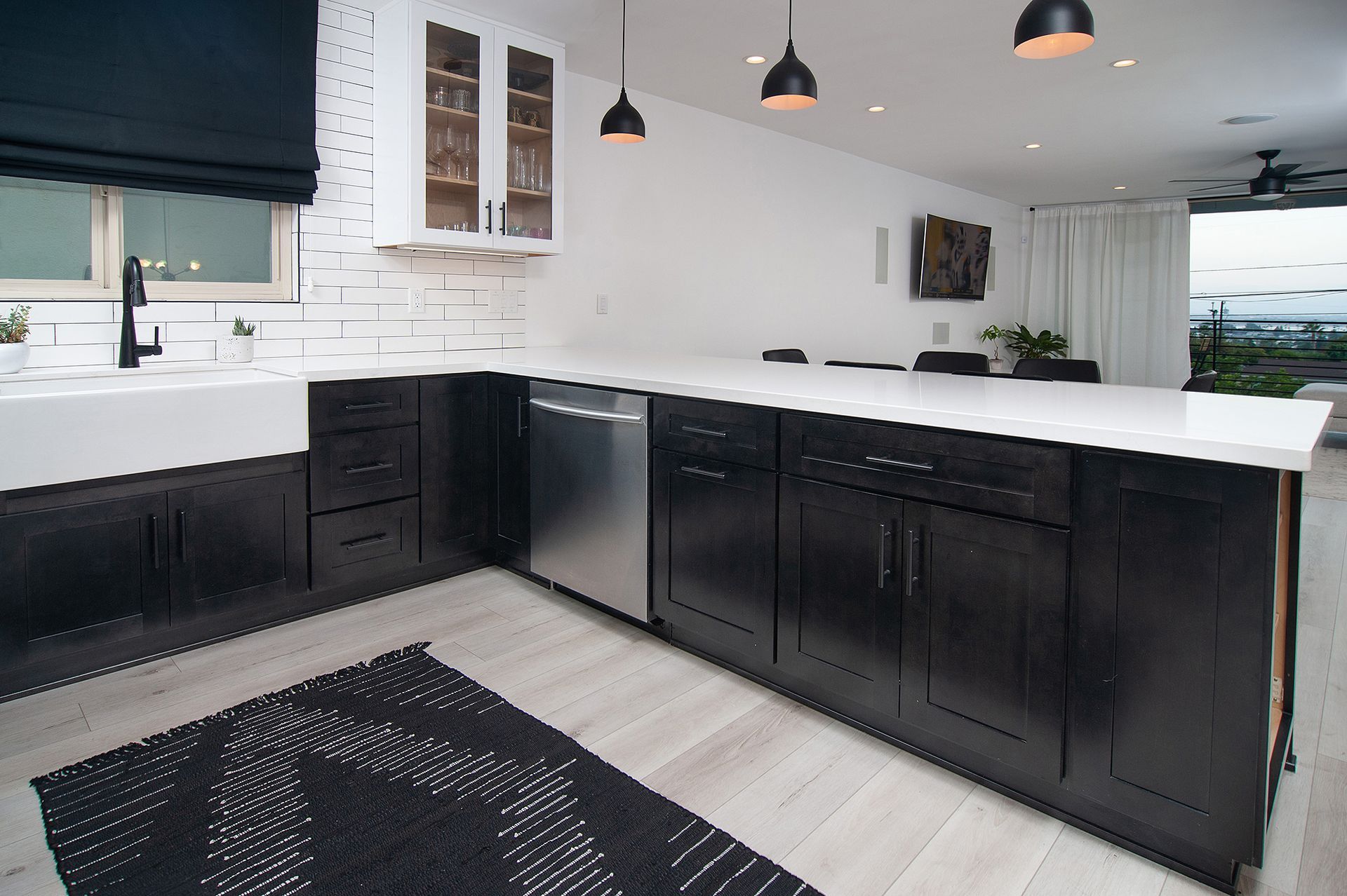 Modern kitchen with black and white cabinets, white countertops, and pendant lights.