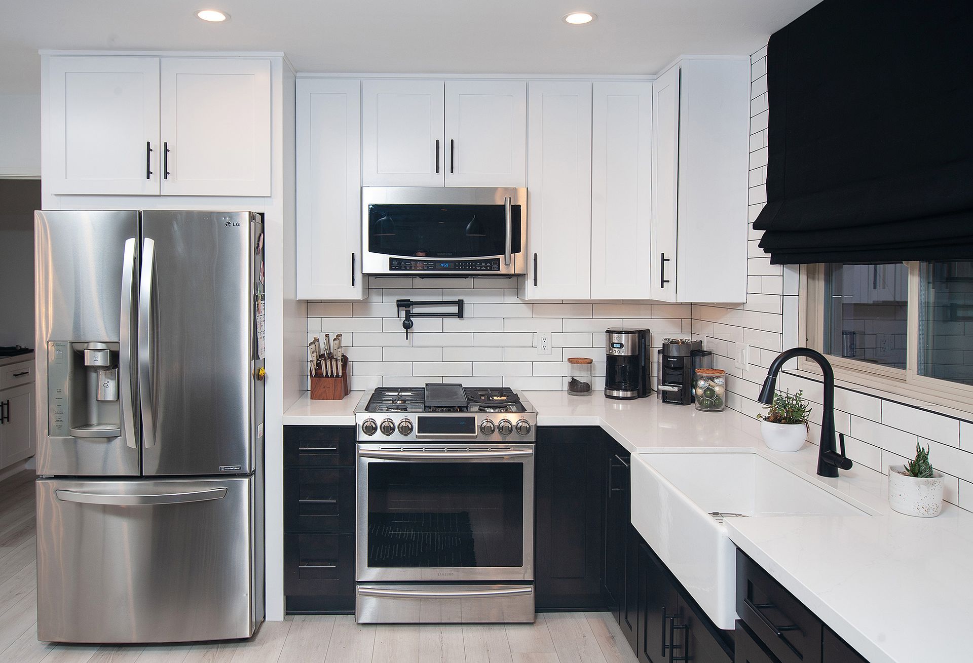 Modern kitchen with stainless steel appliances, white and black cabinets, and white subway tile backsplash.