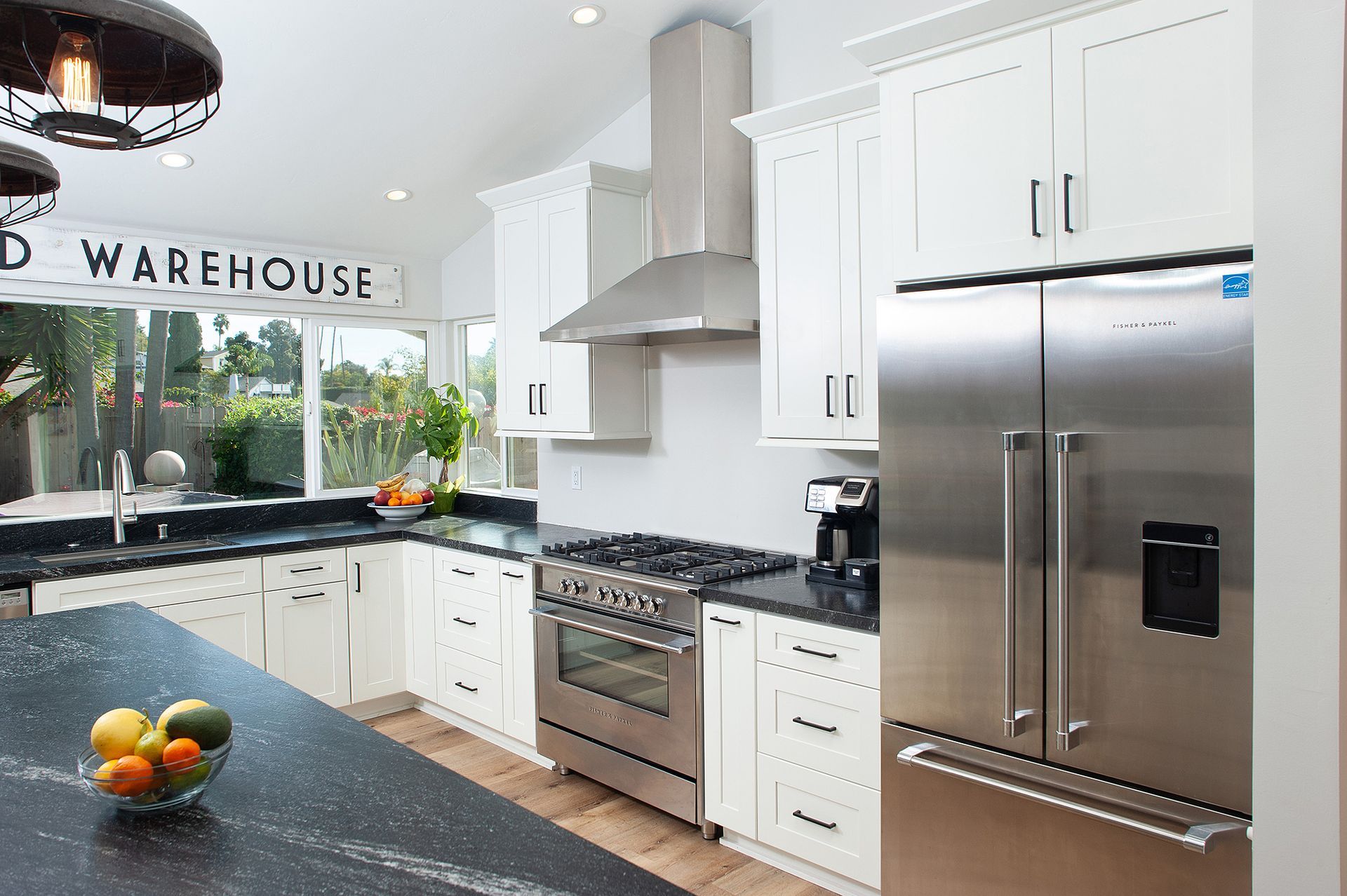 White kitchen with stainless steel appliances and black countertops.