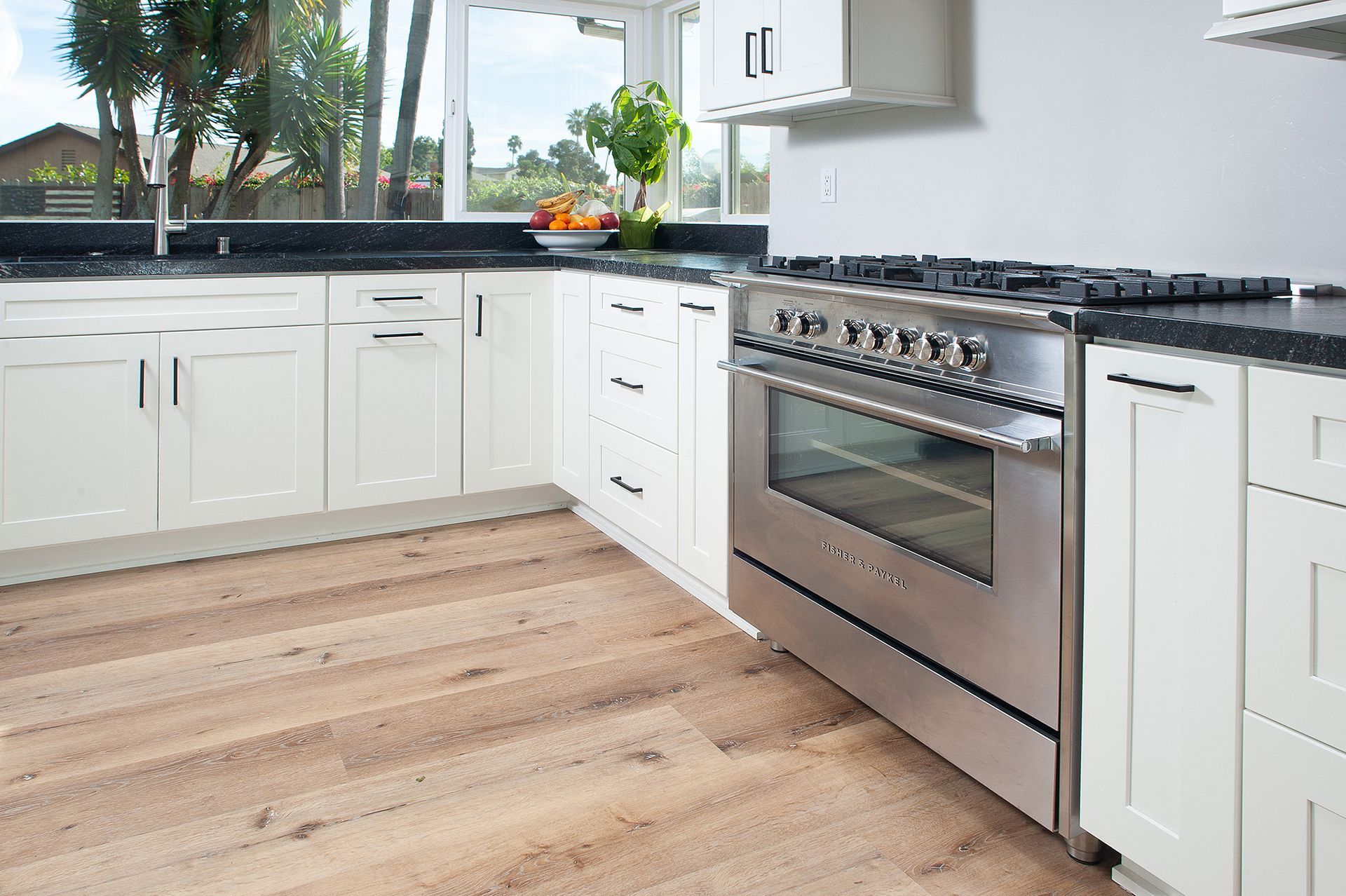Kitchen with white cabinets, stainless steel oven, and light wood floor.