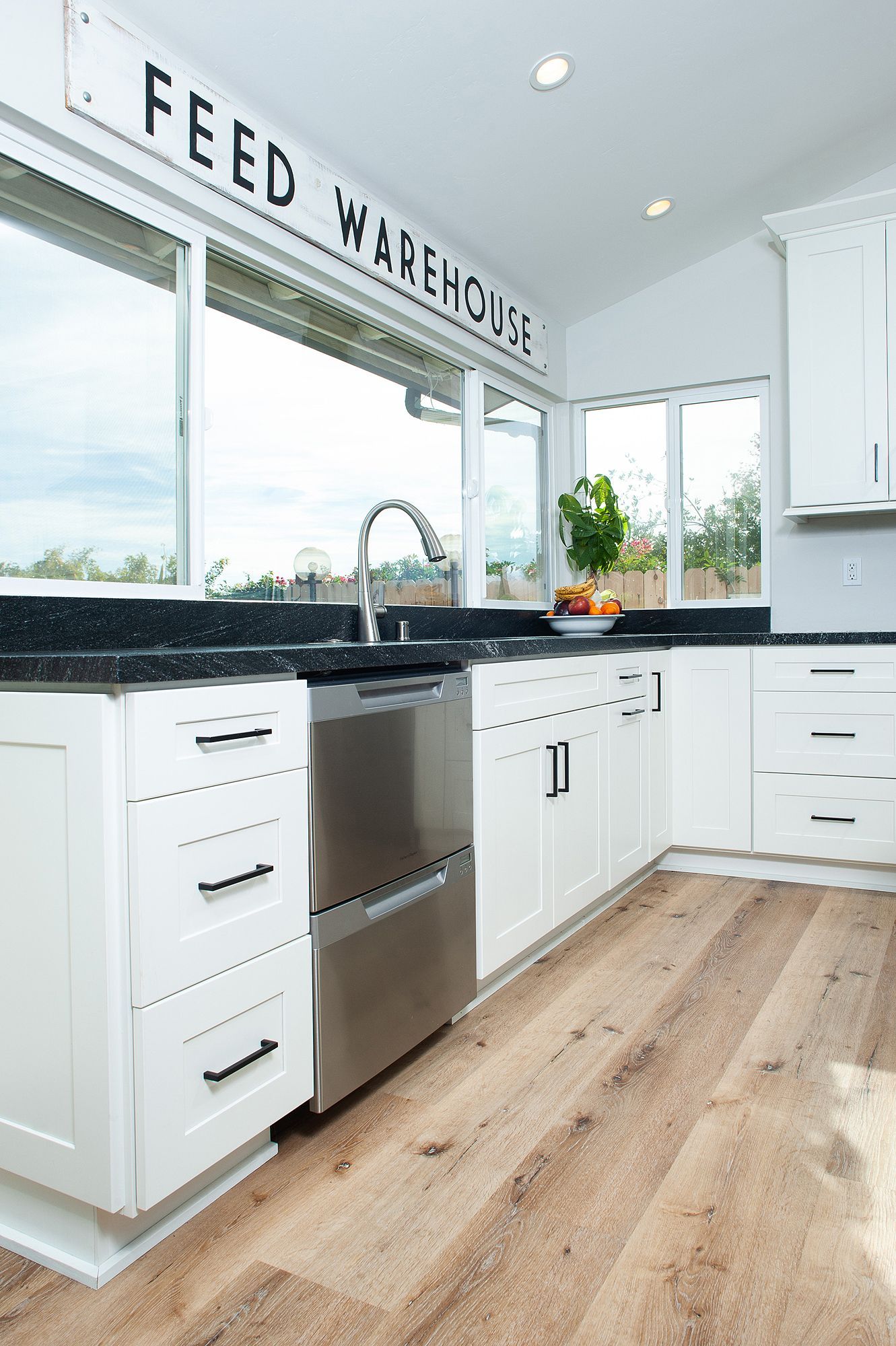 White kitchen with black countertops, stainless steel appliances, and a 