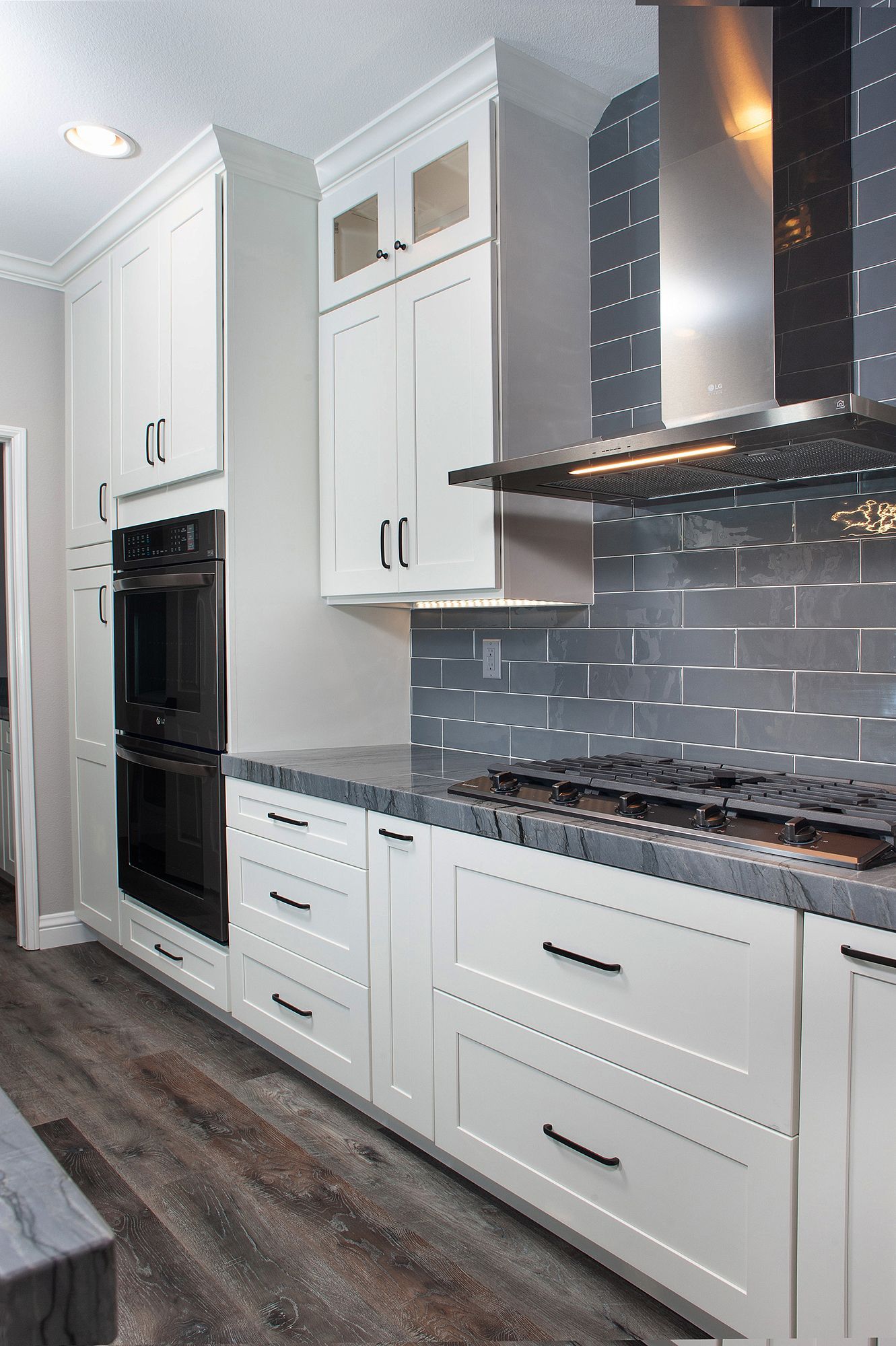 White kitchen cabinets with black appliances and dark gray backsplash.