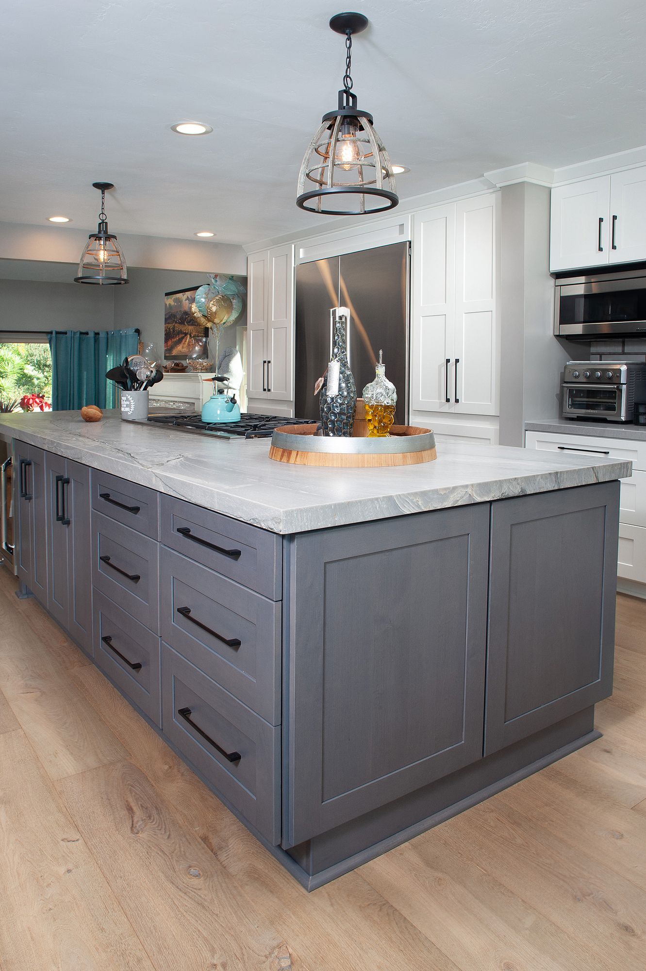 Gray kitchen island with drawers and cabinets, topped with a light-colored countertop.