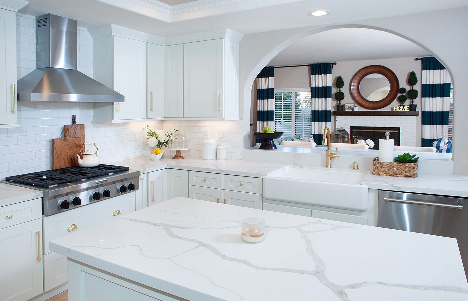 White kitchen with marble countertops, stainless steel appliances, and an arched doorway.