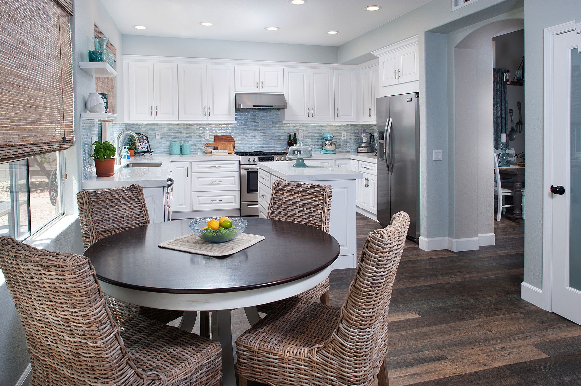 Kitchen with white cabinets, island, and round dining table with patterned chairs.