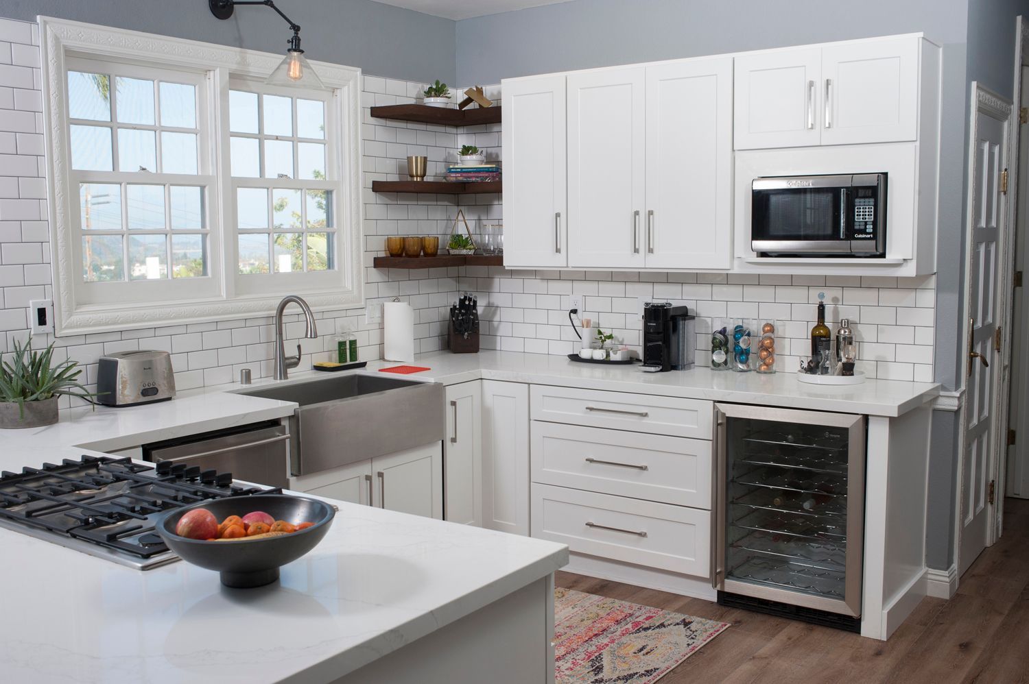 White kitchen with stainless steel appliances, subway tile backsplash, and open shelving.