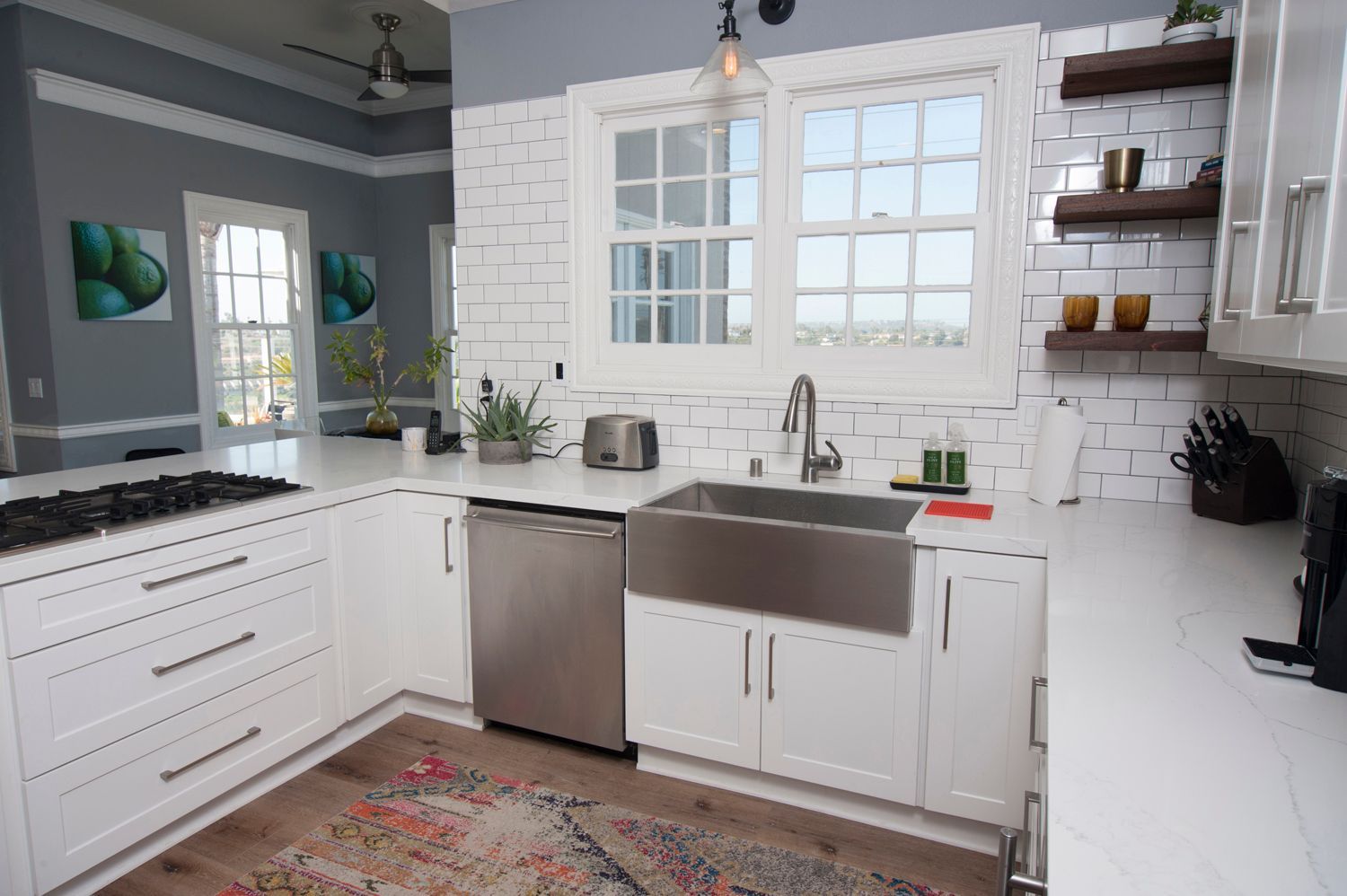 White kitchen with stainless steel appliances, white brick wall, and wooden shelves.