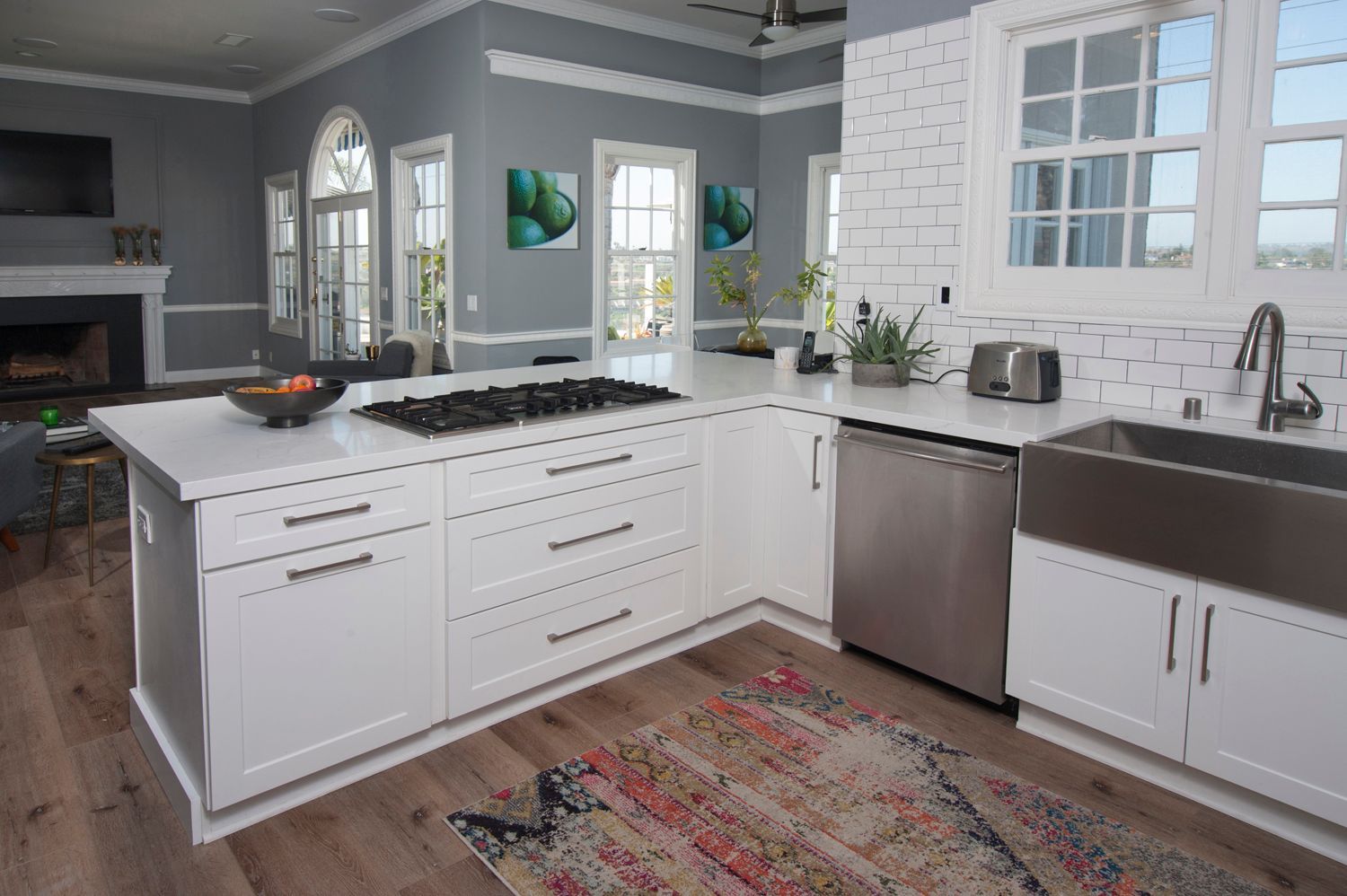 Bright, spacious kitchen with white cabinets, gray walls, and a stainless steel sink.