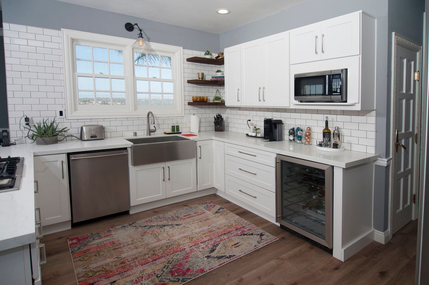 White kitchen with stainless steel appliances, butcher block countertops, and a rug.