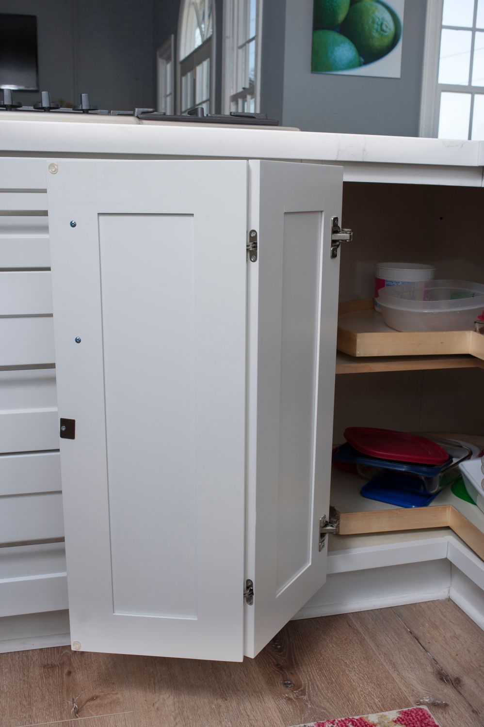 White kitchen cabinet, open, revealing shelves with items.