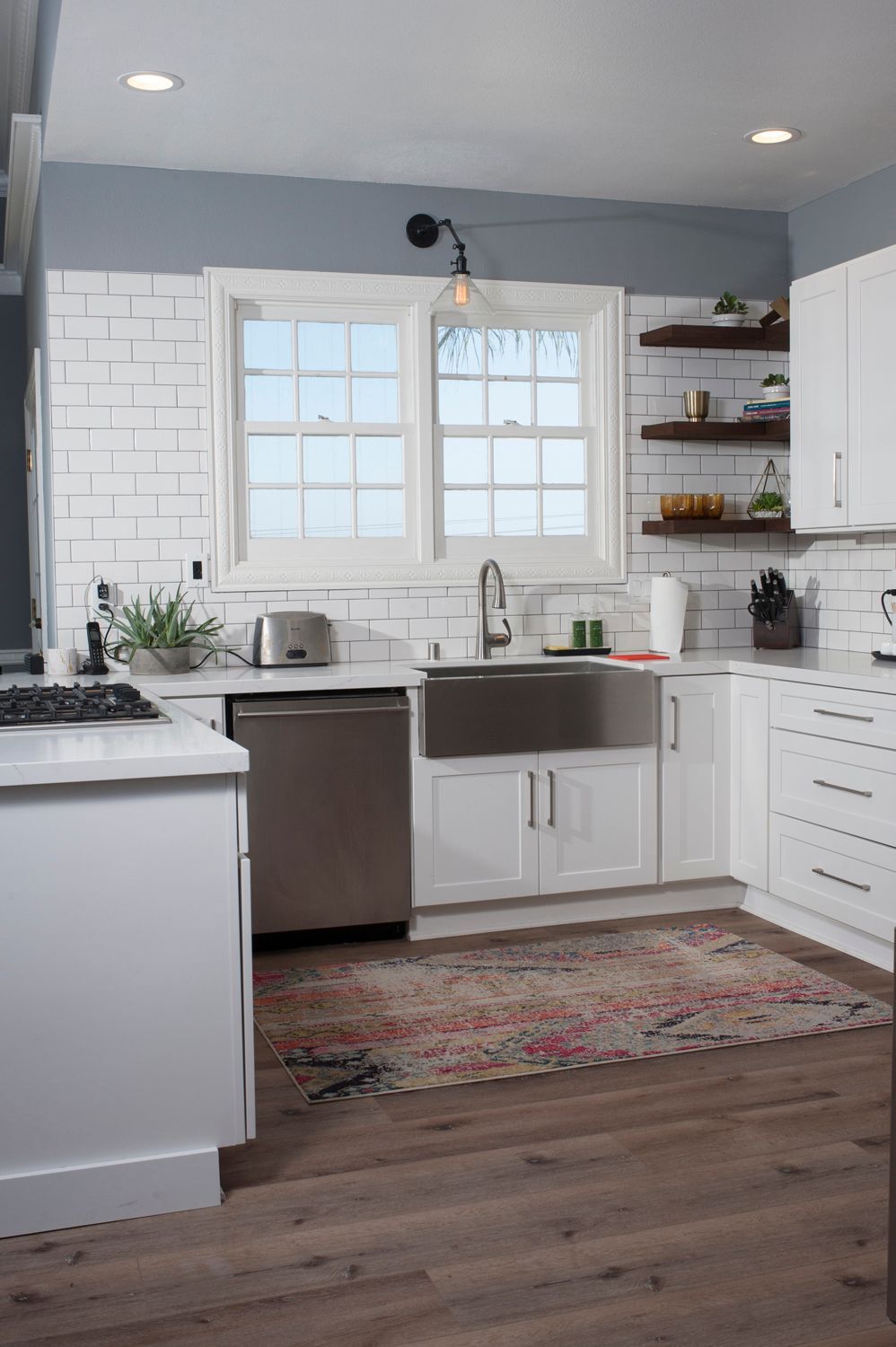 Bright kitchen with white cabinets, stainless steel sink, and a rug.