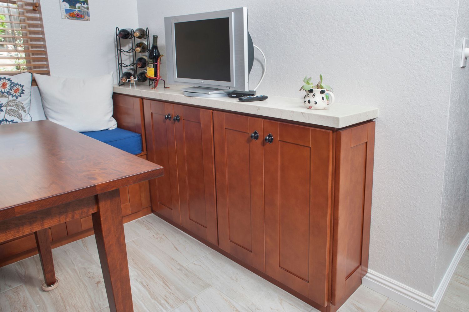 Wooden cabinet with countertop, TV, and table in a dining area.