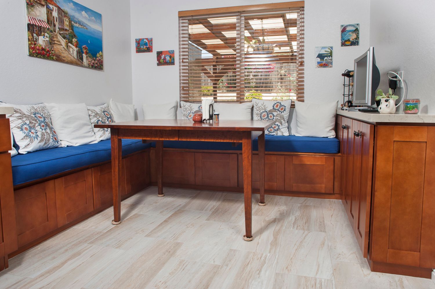 Cozy cafe seating with a wooden table, blue cushions, and a window with blinds.