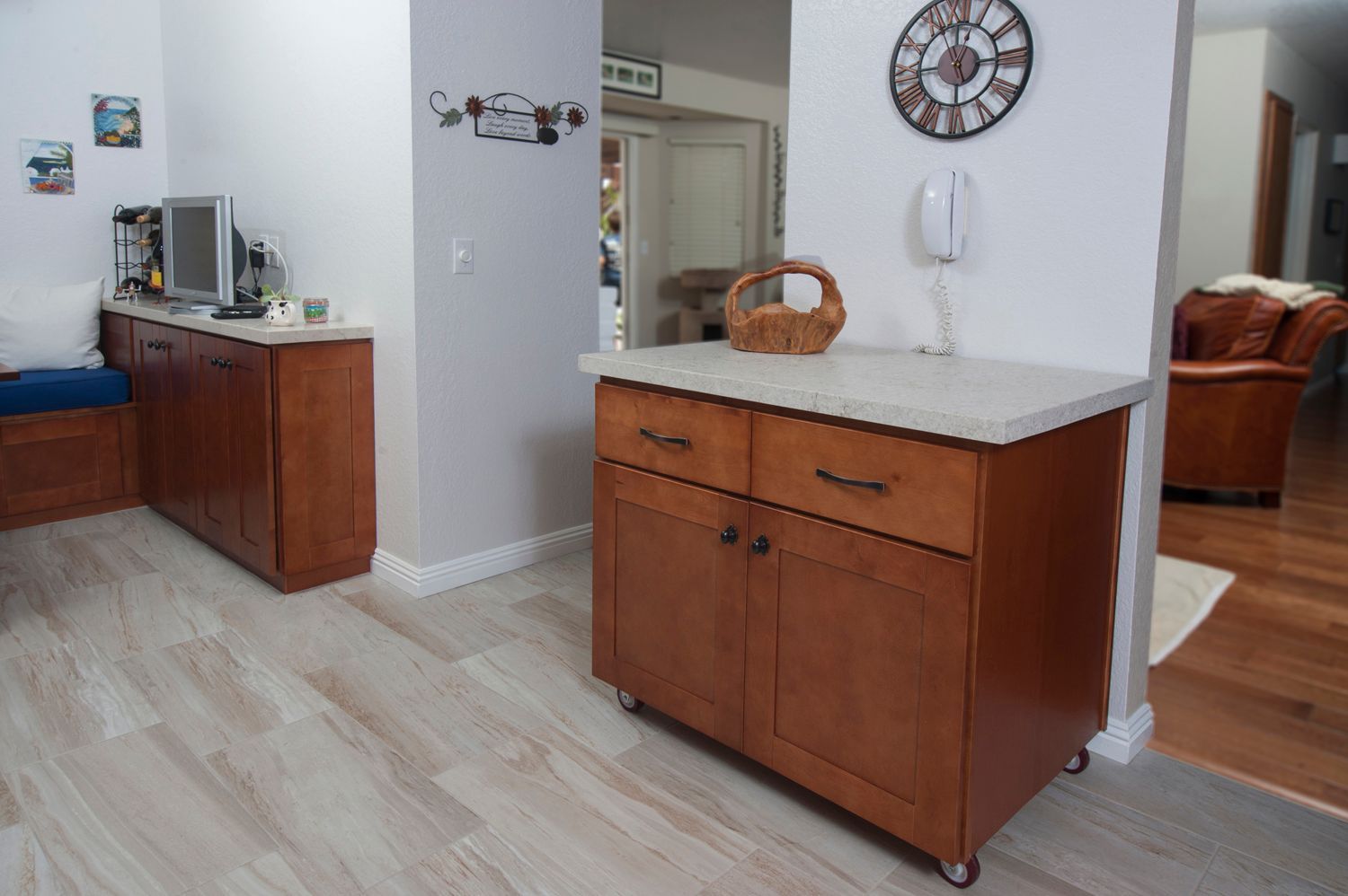 Kitchen island with cabinet, countertop, and casters. Other cabinetry and decor in the background.