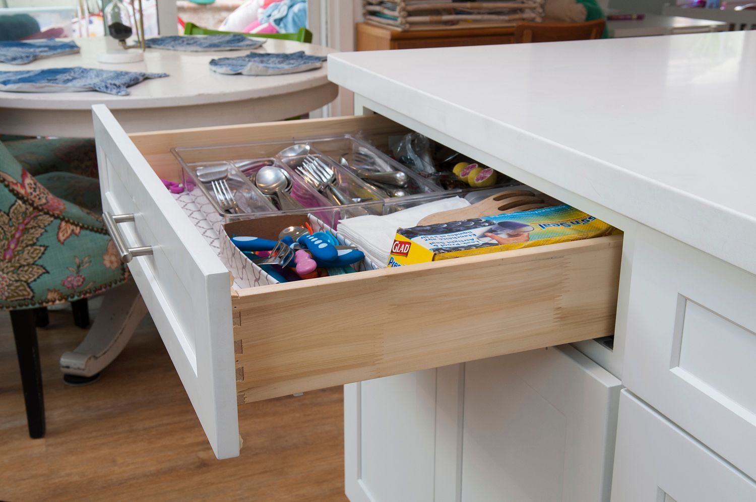 Drawer of utensils and cutlery in a white kitchen island.