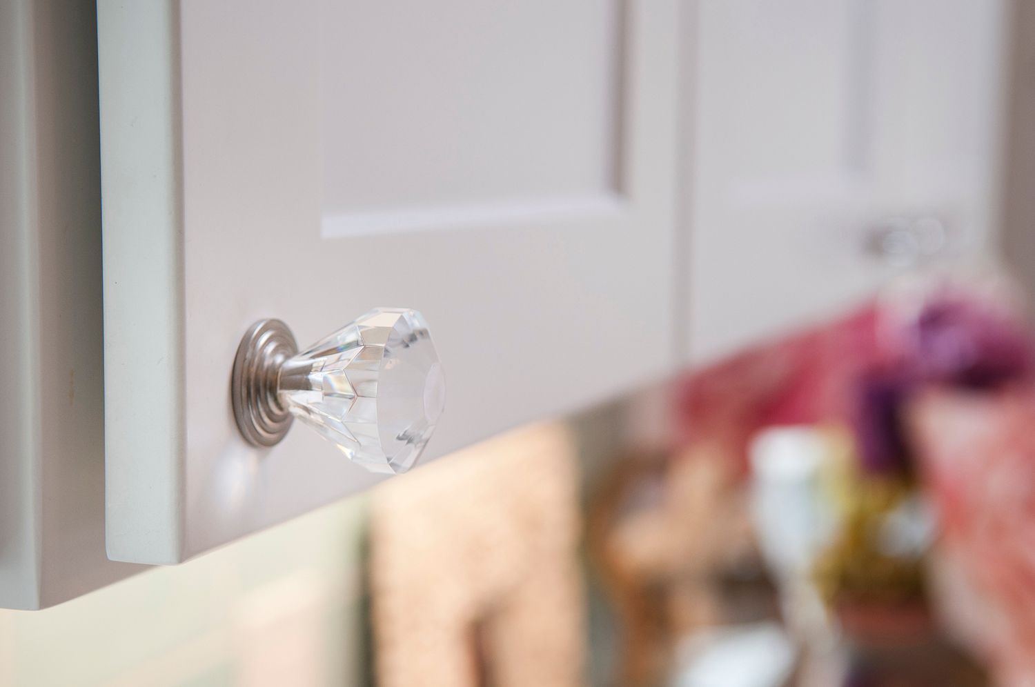 Crystal cabinet knob on a white cabinet door.