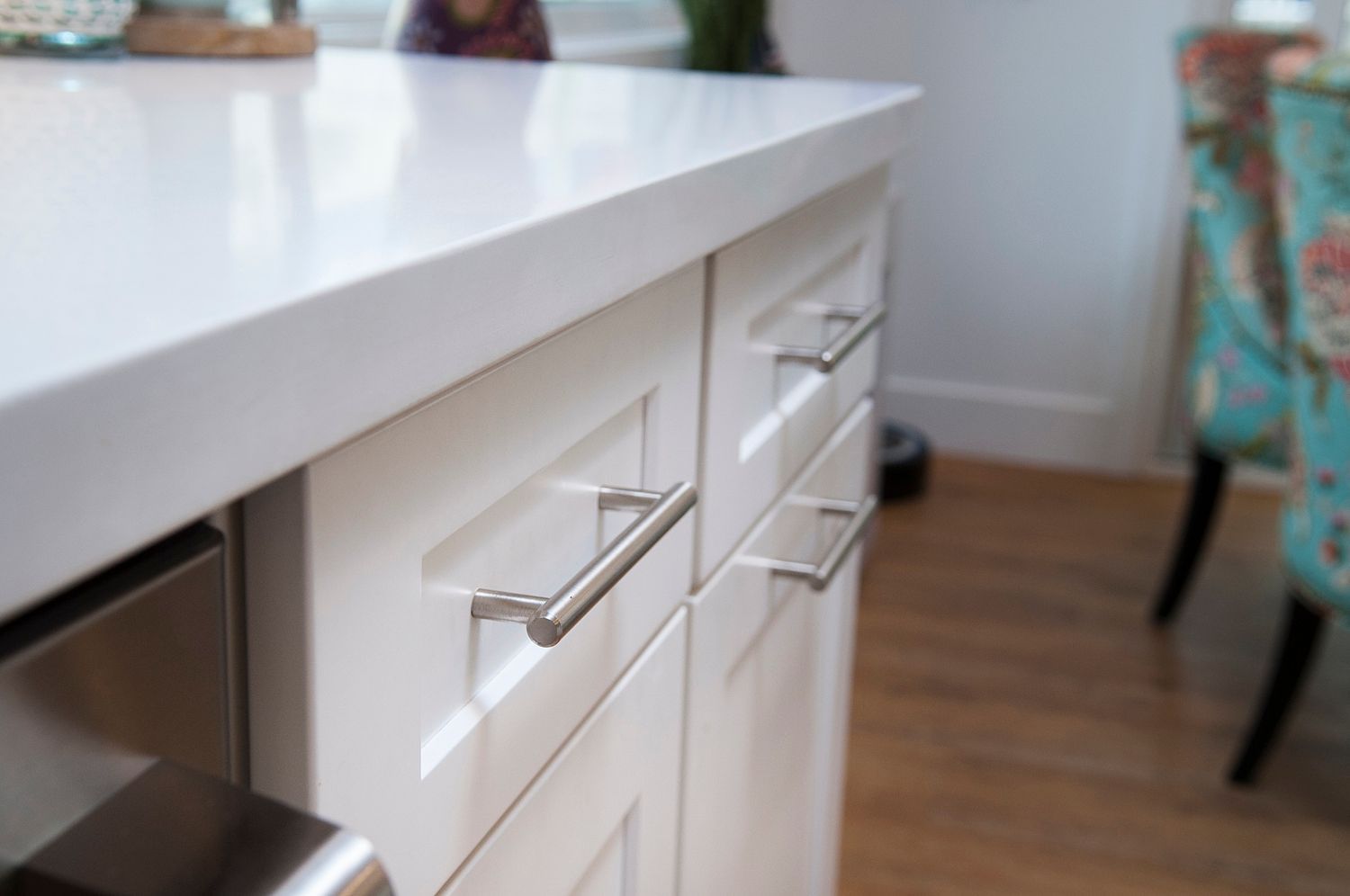 White kitchen cabinets with silver handles, topped by a bright, glossy white countertop.