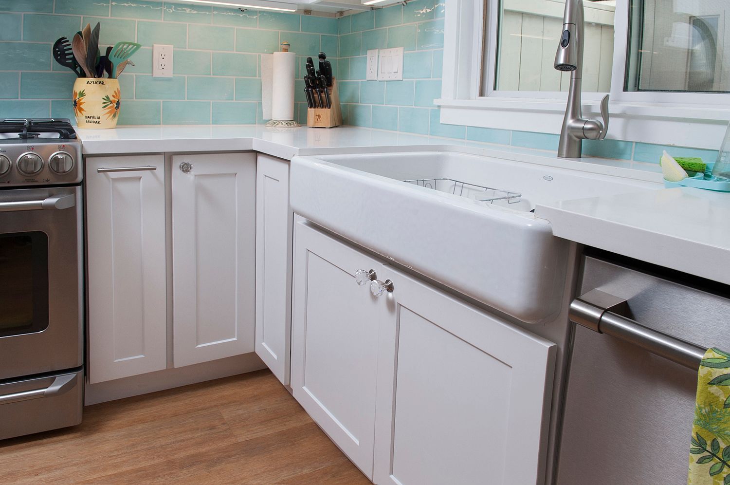 White kitchen with a large sink, white cabinets, and blue backsplash.
