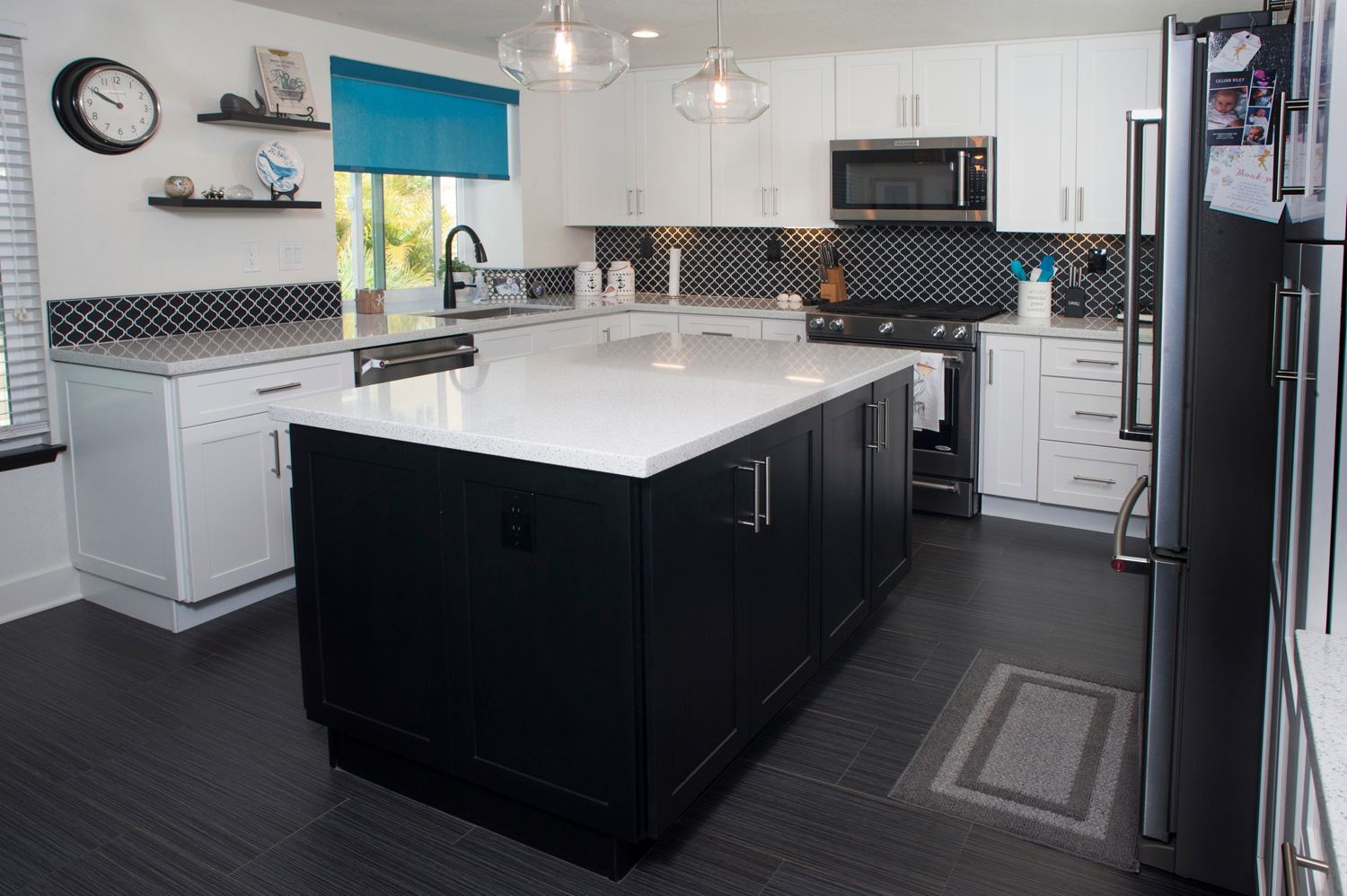 Modern kitchen with white and black cabinets, a large island, and dark flooring.
